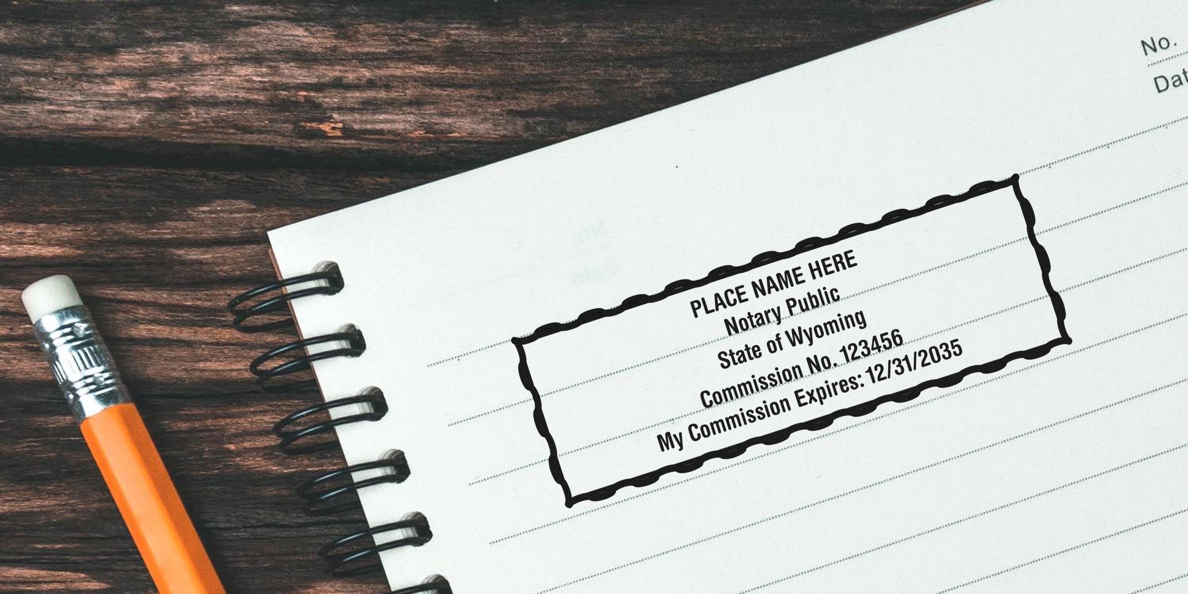 Affordable Wyoming notary stamps on a notebook page with a pencil, showcasing Wyoming notary supplies on a wooden table.