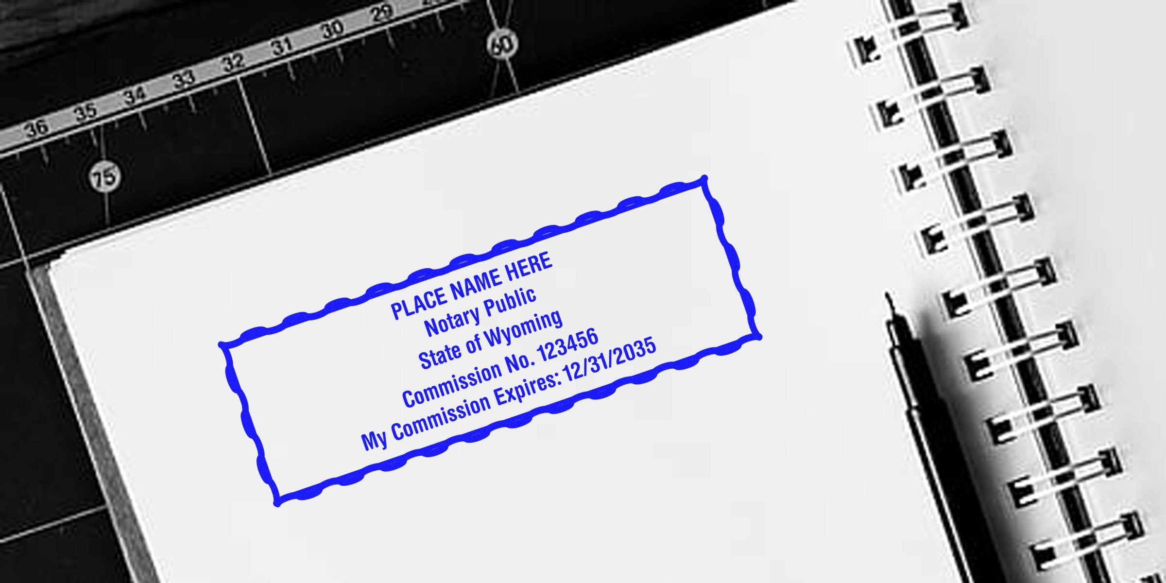Wyoming notary seal with commission expiration date stamped on notebook page next to black pen and ruler; order your notary seal online today.