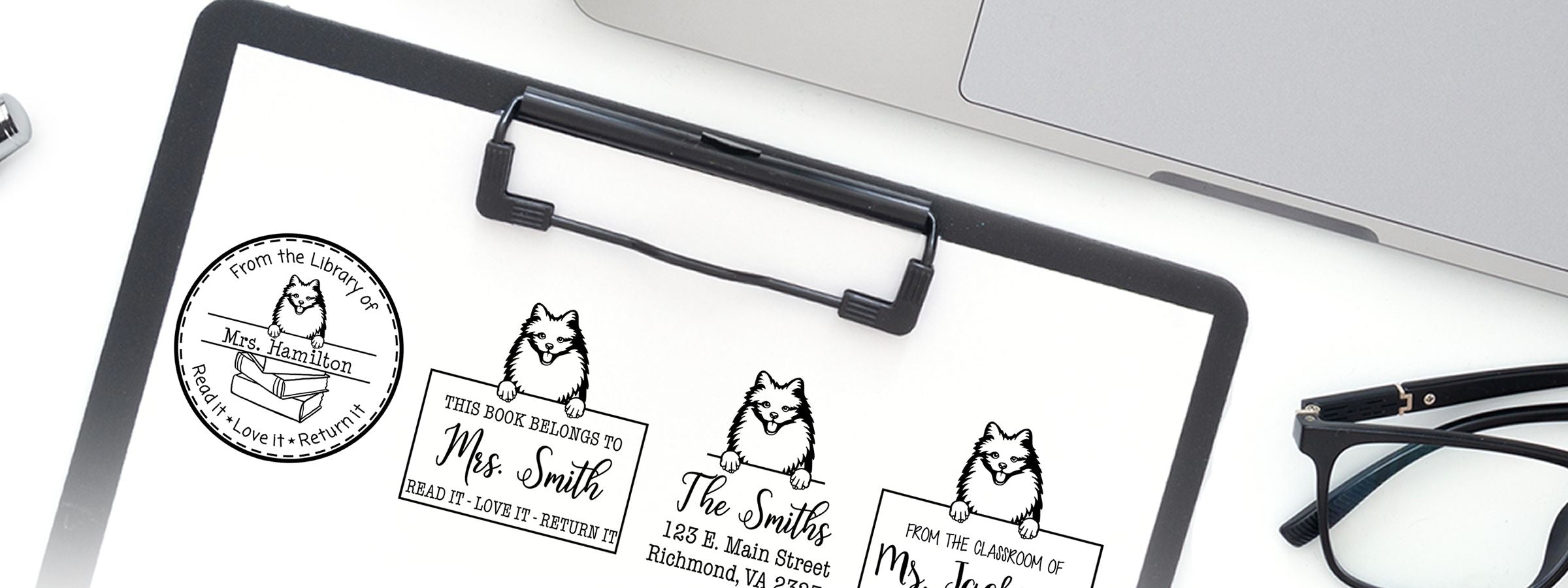 Clipboard with custom bookplate designs, including an American Eskimo Dog Stamps and Custom Seals sheet showing a dog holding signs, plus laptop and eyeglasses.