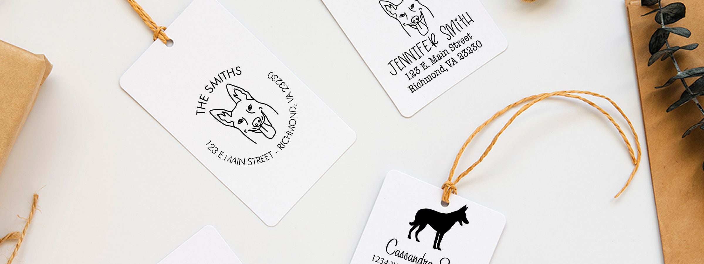 Flat lay of white pet gift tags with dog logos and custom names, tied with twine; Belgian Malinois Dog Stamps and Custom Seals on kraft paper.