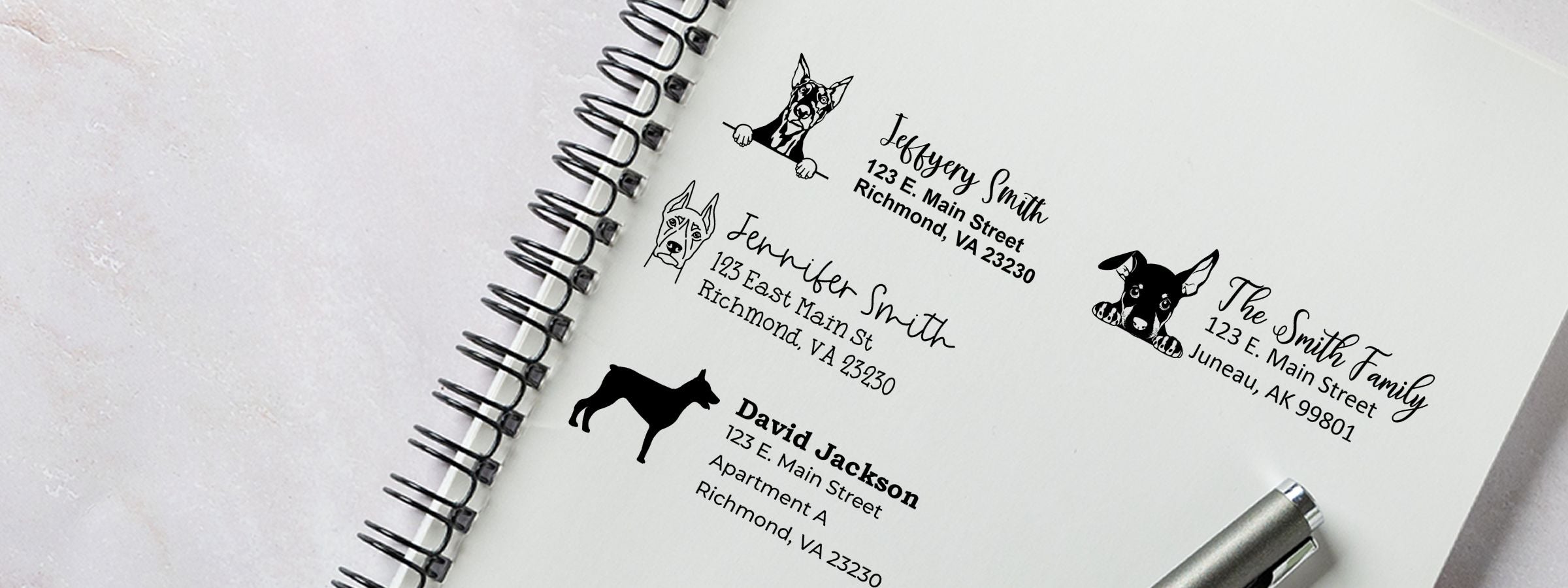 Spiral notebook with Doberman Dog Stamps and Custom Seals address labels, names, and addresses, plus a pen at bottom right.