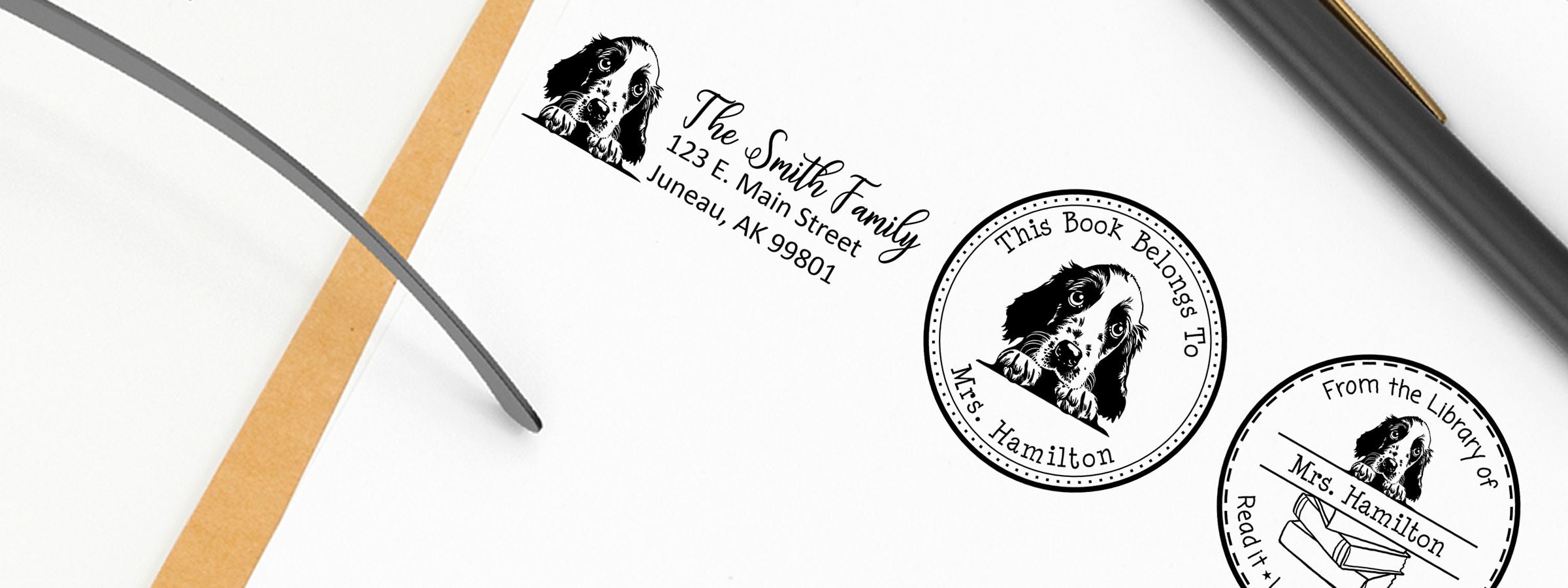 Open notebook with pencil and ribbon bookmark, showing English Setter Dog Stamps and Custom Seals for The Smith Family and Mrs. Hamilton.