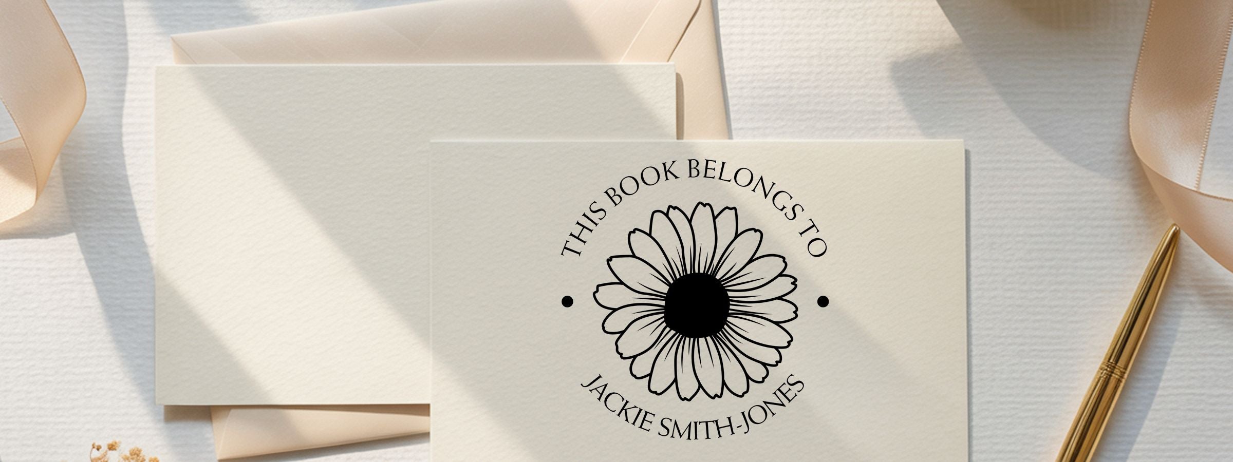 Bookplate card reading “THIS BOOK BELONGS TO JACKIE SMITH-JONES” on cream stationery with envelopes, ribbon, gold pen, and Floral and Botanical Designer Stamps.