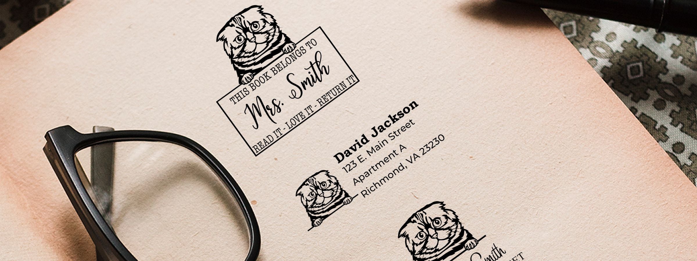 Close-up of custom bookplate and address labels with a cartoon owl, black eyeglasses, and Foldex Cat Stamps and Custom Seals.
