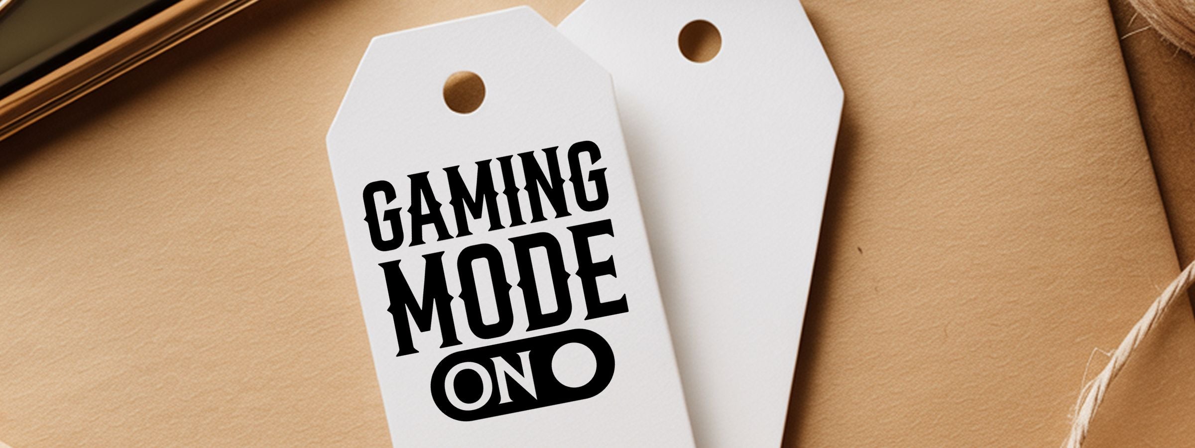 Two white hanging tags on a tan background; front tag says “GAMING MODE ON” in black, from Gamer Craft Stamps.