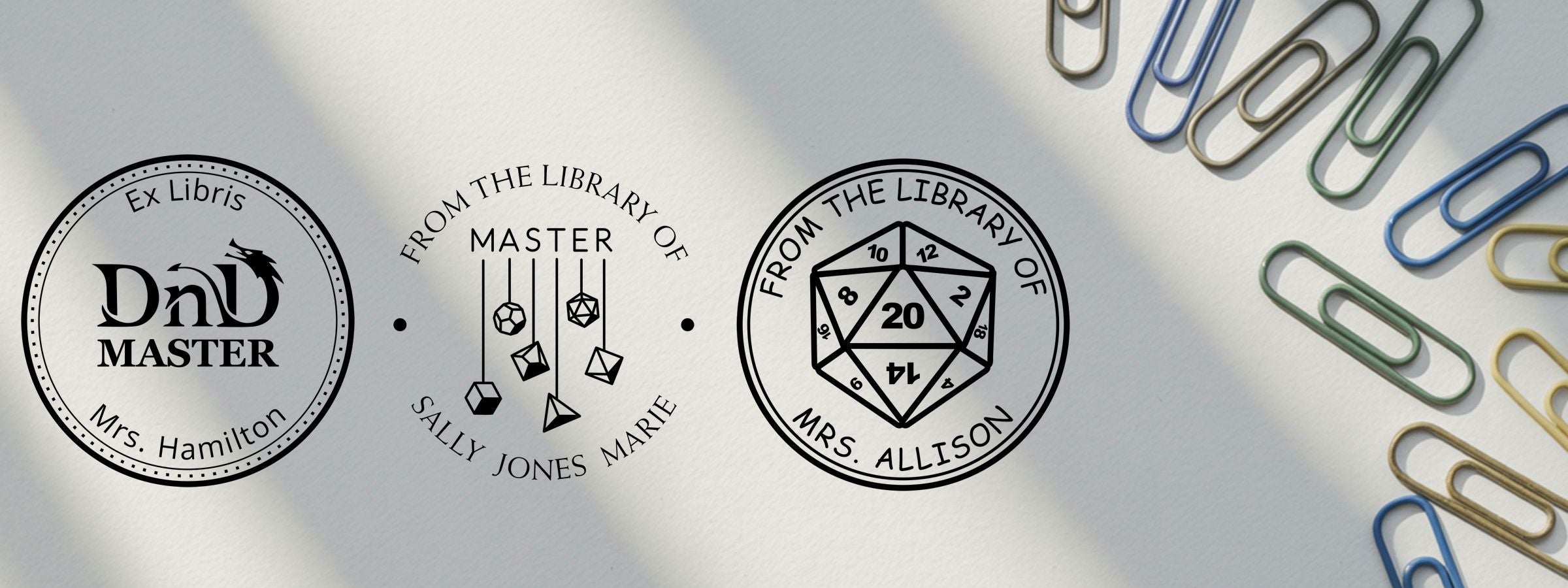 Three Gamer Designer Stamps on white paper with colorful paper clips: DnD Master, Sally Jones Marie, and Mrs. Allison d20 bookplates.