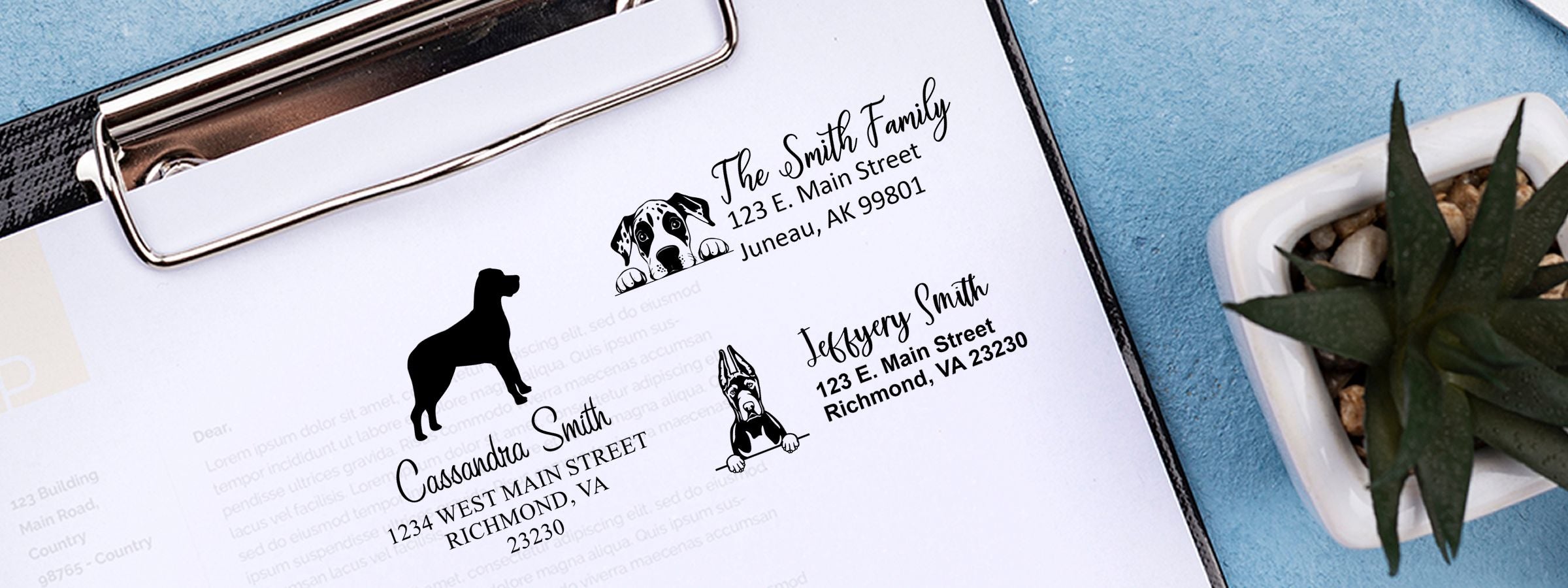 Clipboard with custom pet address labels, dog silhouettes, family names, and Great Dane Dog Stamps and Custom Seals beside a potted succulent on a blue surface.