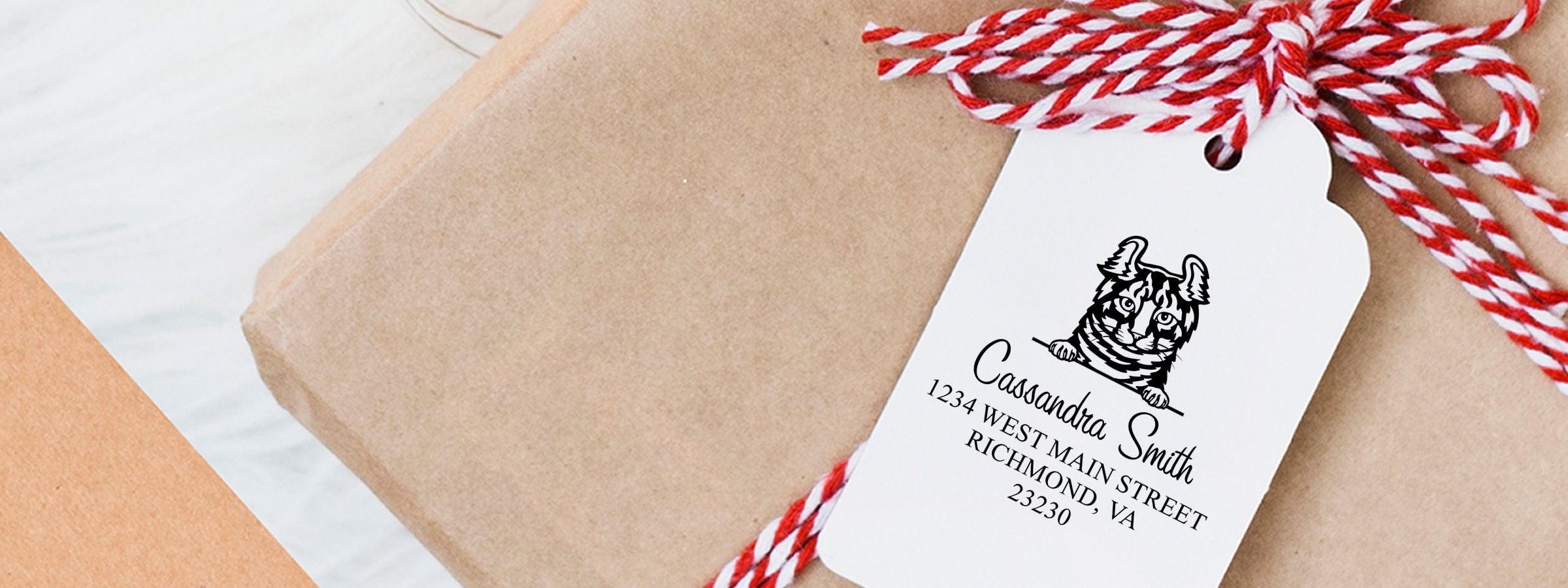 Wrapped gift tag tied with red-and-white string, tiger illustration, and Cassandra Smith; Highlander Cat Stamps and Custom Seals.