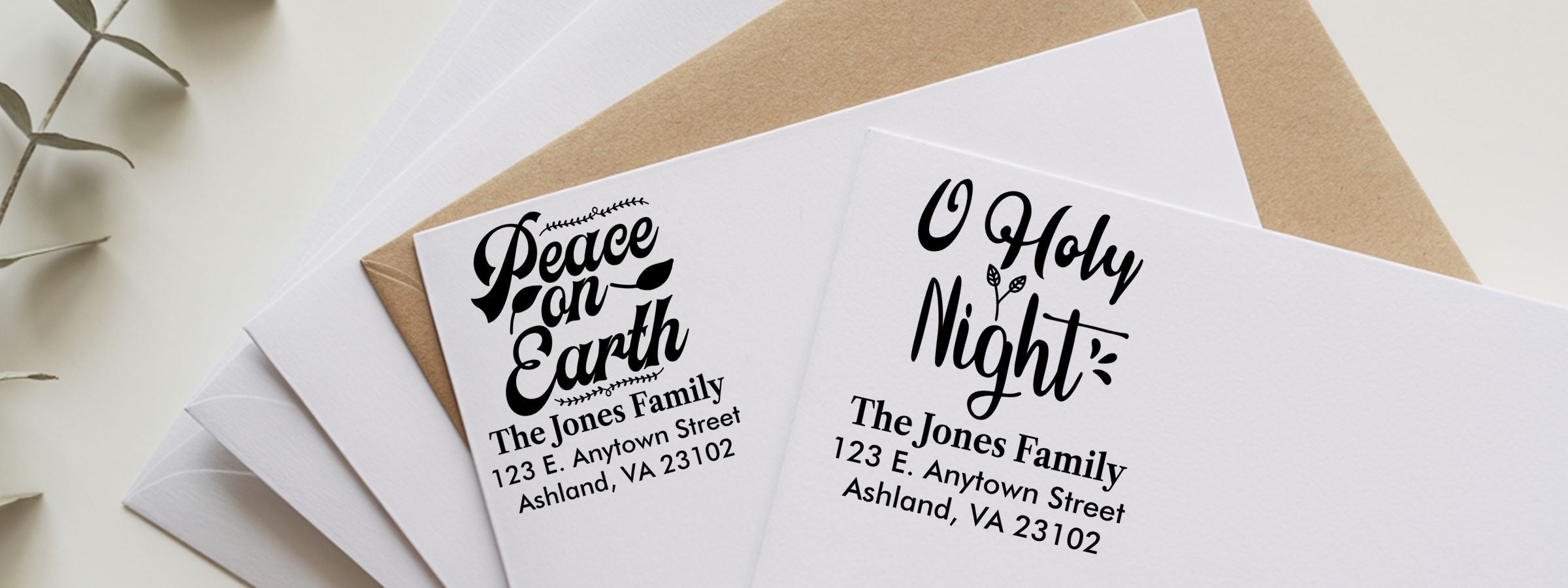 Overhead view of white and kraft envelopes with “Peace on Earth” and “O Holy Night” labels for The Jones Family, Holiday and Seasonal Designer Stamps.