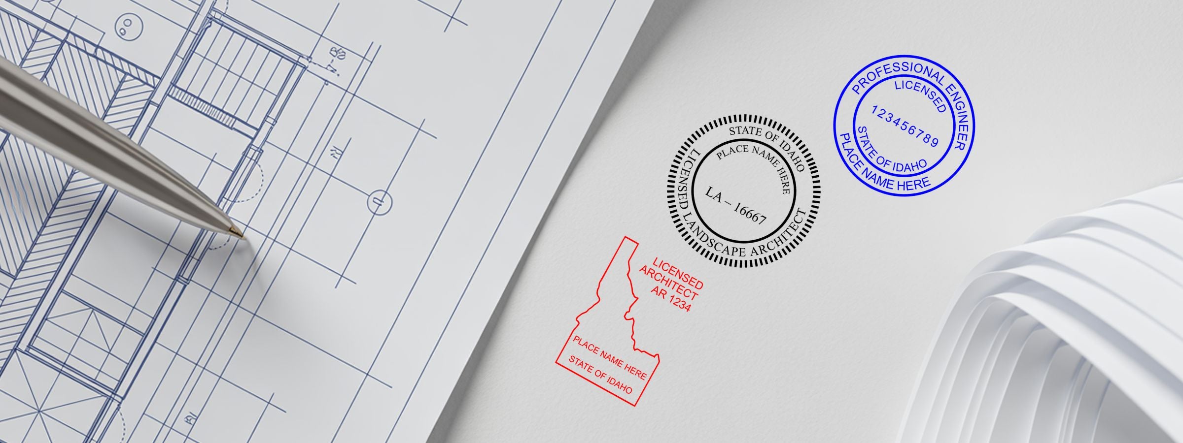 Architectural blueprint with pen, rolled plans, and Idaho Professional Seals and Stamps for engineer, architect, and landscape architect.