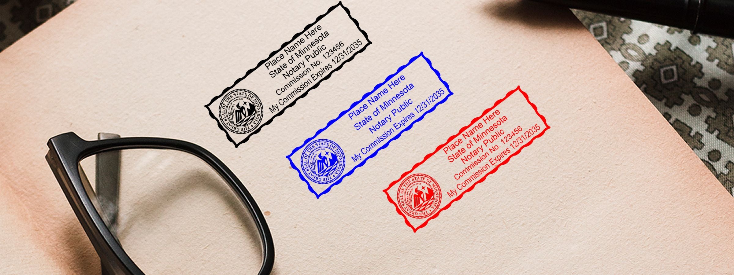 Close-up of eyeglasses beside black, blue, and red Minnesota notary stamp designs from Minnesota Notary Supplies, Stamps and Seals.