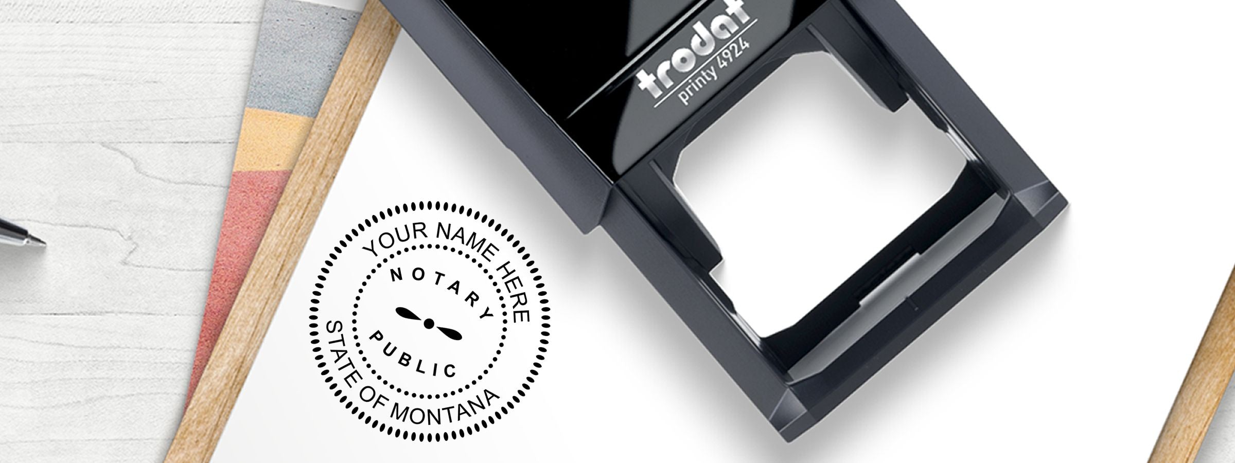 Black Trodat Printy 4924 self-inking notary stamp beside Montana notary imprint on white paper; Montana Notary Supplies, Stamps and Seals