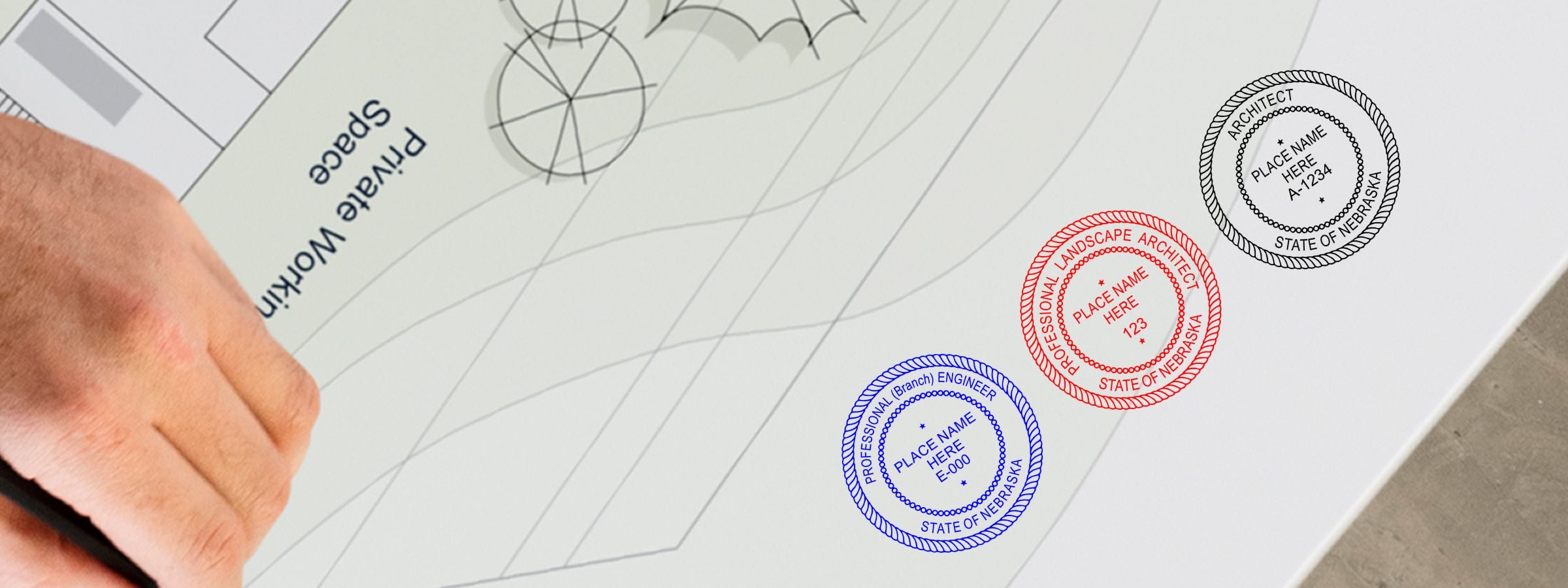 Hand holding pencil over architectural site plan with black, red, and blue stamp seals; Nebraska Professional Seals and Stamps.