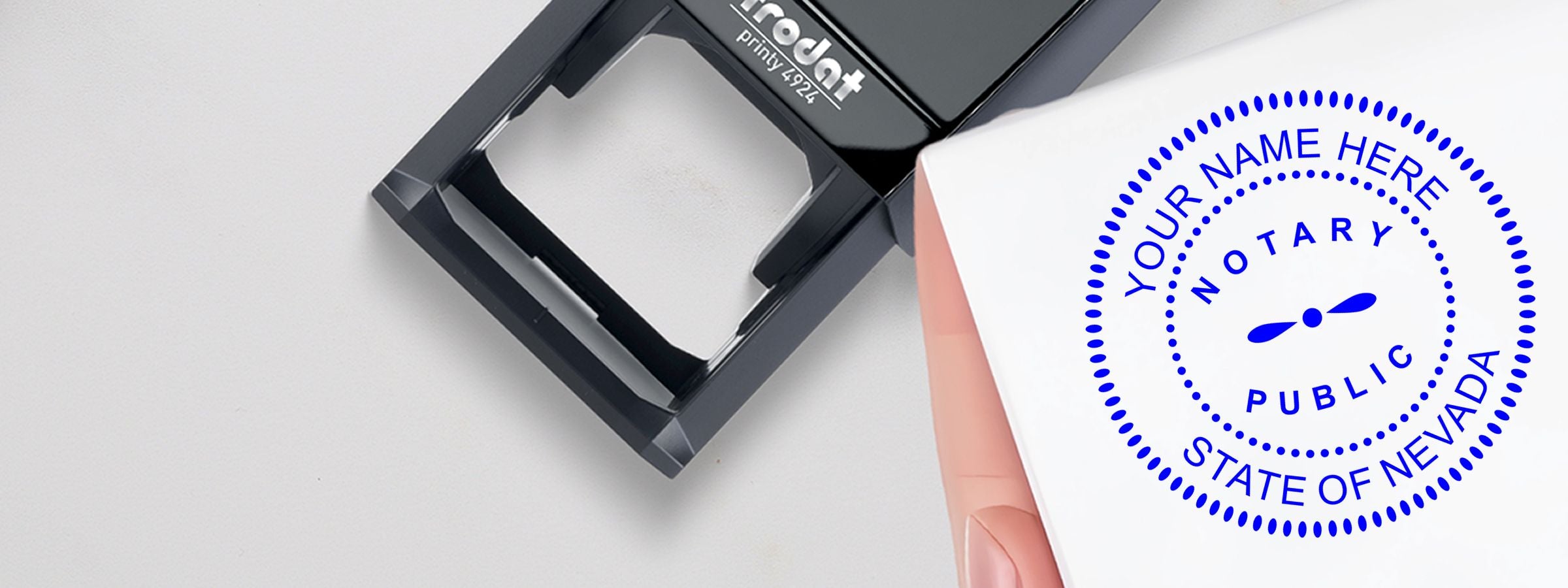 Close-up of a black self-inking notary stamp beside a blue Nevada seal reading “Your Name Here” for Nevada Notary Supplies, Stamps and Seals.