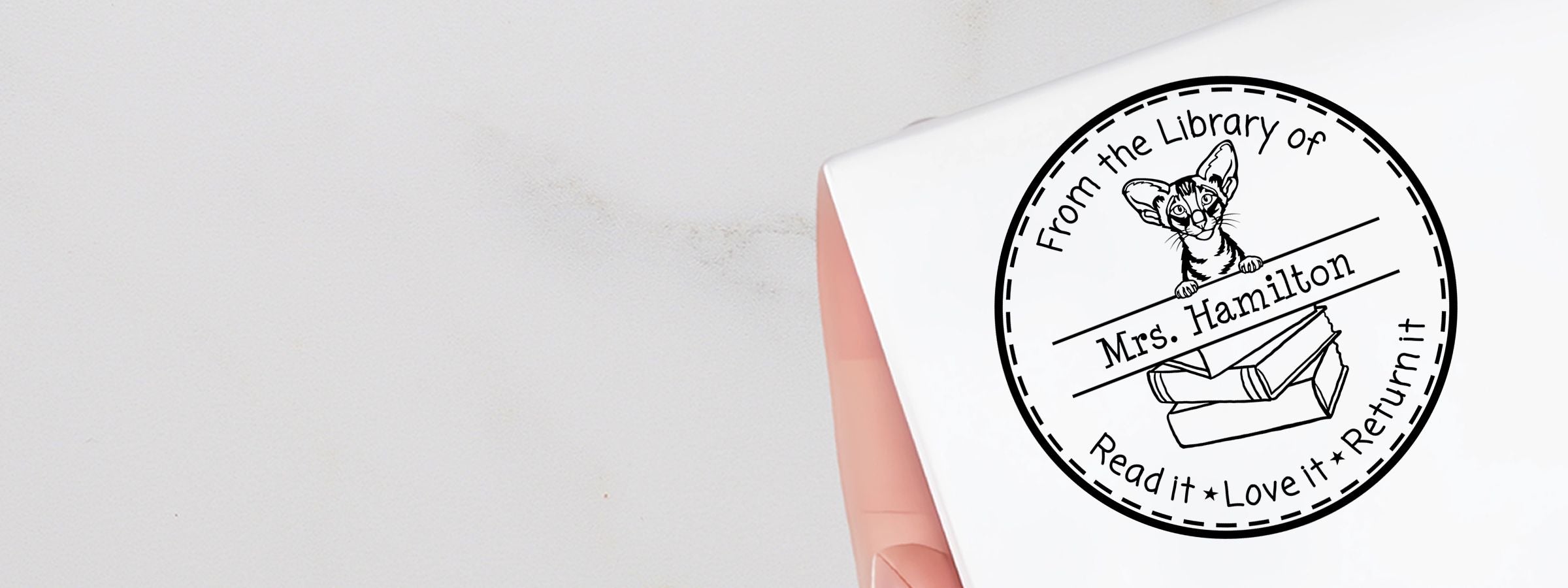 White fabric with a black library logo, Oriental Shorthair Cat Stamps and Custom Seals, cat above books and “From the Library of Mrs. Hamilton.”