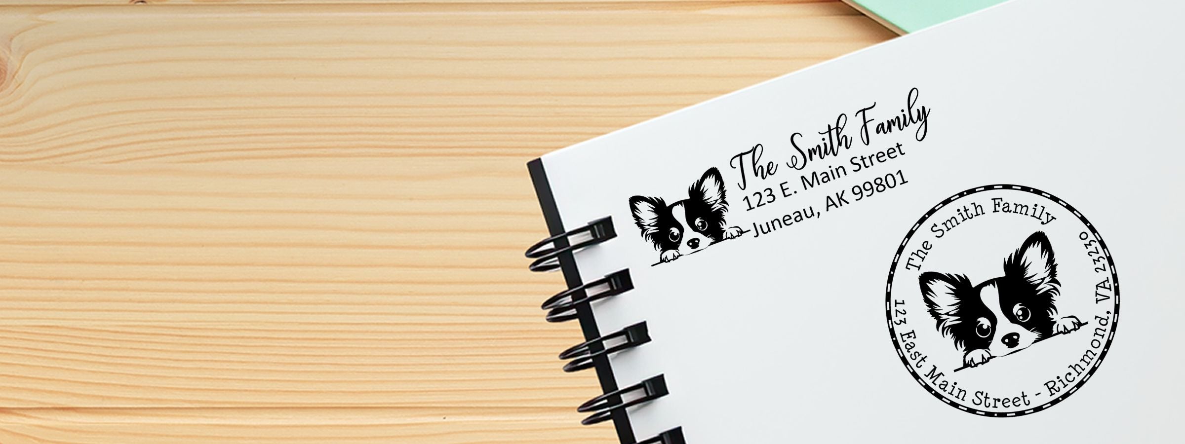 White spiral notebook with Papillon Dog Stamps and Custom Seals, black-and-white dog logo, personalized family address, and circular stamp design.