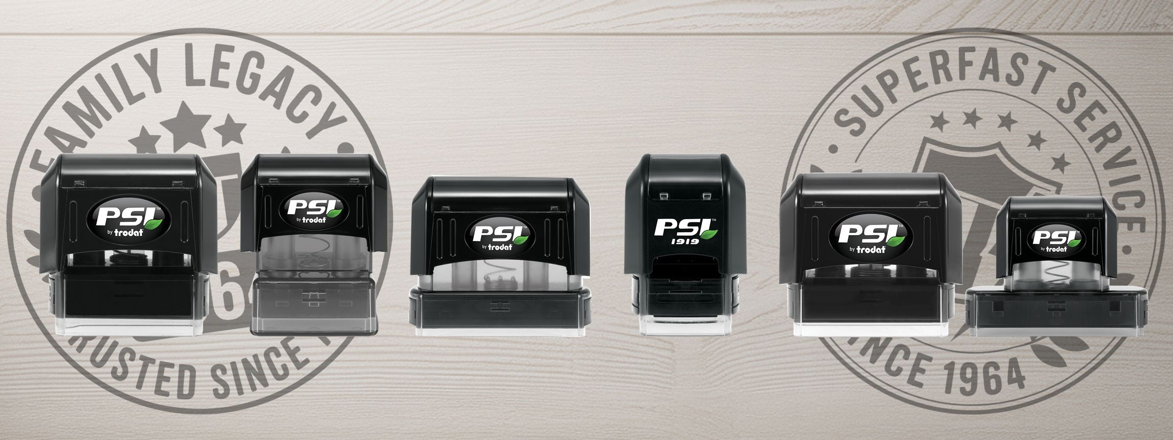 Row of six black PSI Pre-Inked Stamps on wood background with faded Family Legacy and Superfast Service seal graphics.