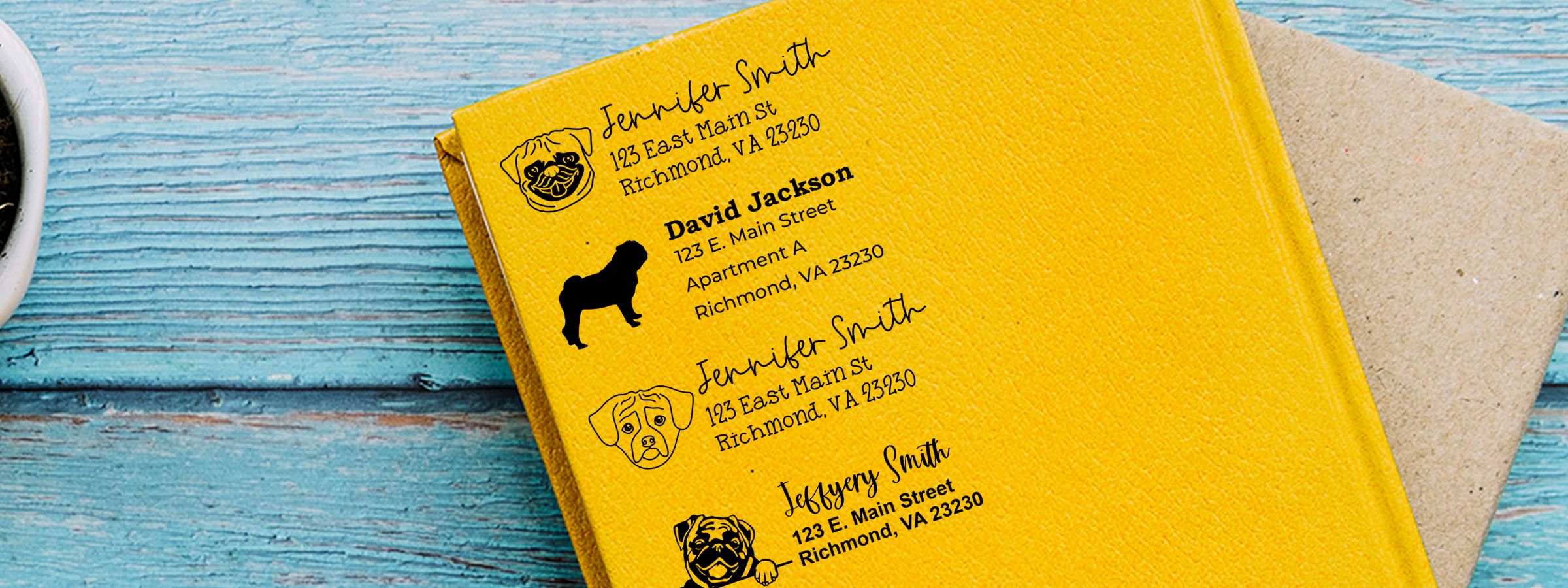 Yellow mailing envelope on blue wood with sample dog address labels, Pug Dog Stamps and Custom Seals, and a kraft envelope behind.