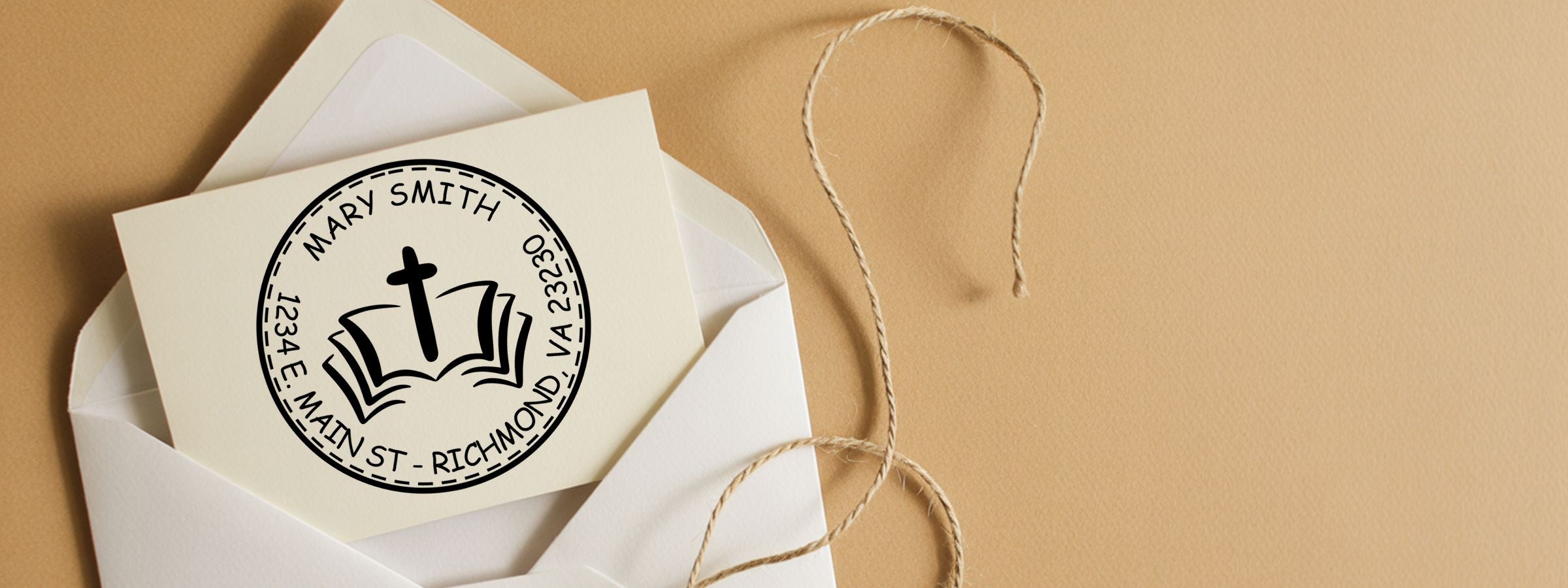 Open white envelope with cream church-logo card and address stamp on tan background, twine loop beside it; Religious and Faith Designer Stamps.