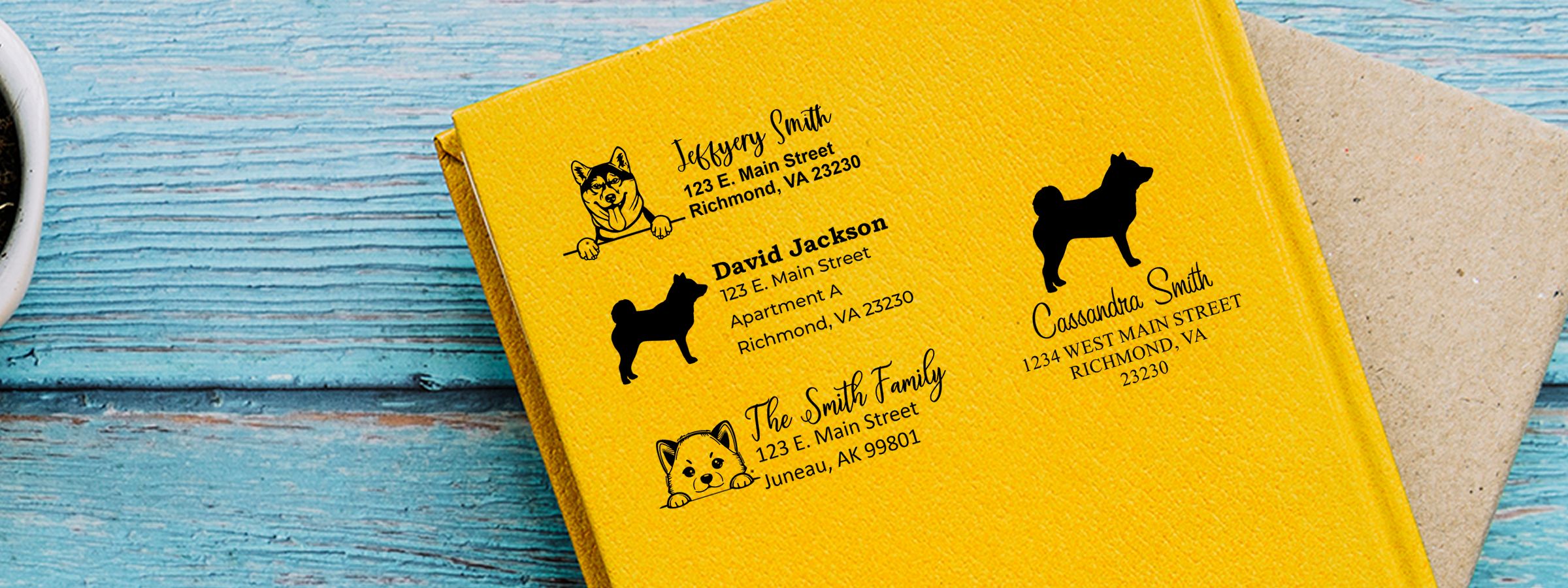 Yellow personalized notebook with dog illustrations and mailing addresses, featuring Shiba Inu Dog Stamps and Custom Seals on a blue wood surface.