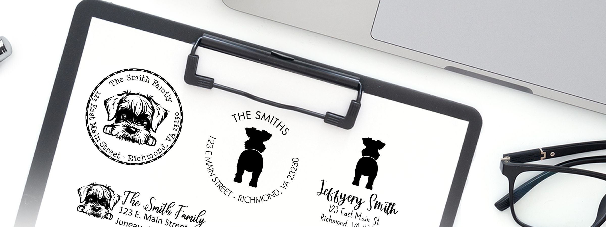 Clipboard holding custom black-and-white dog family address logo designs, with laptop and eyeglasses nearby; Standard Schnauzer Dog Stamps and Custom Seals.