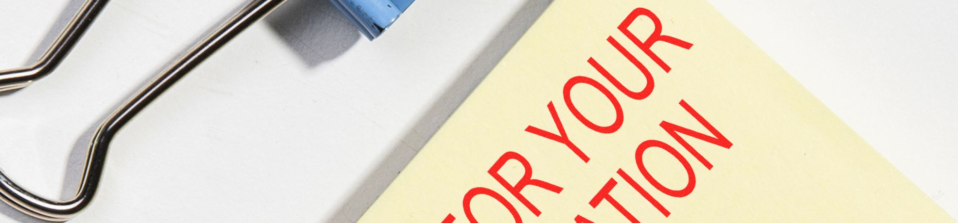 Large Wooden Handle Stock Stamps beside a pale yellow note clipped with a blue binder clip reading “FOR YOUR ATTENTION.”
