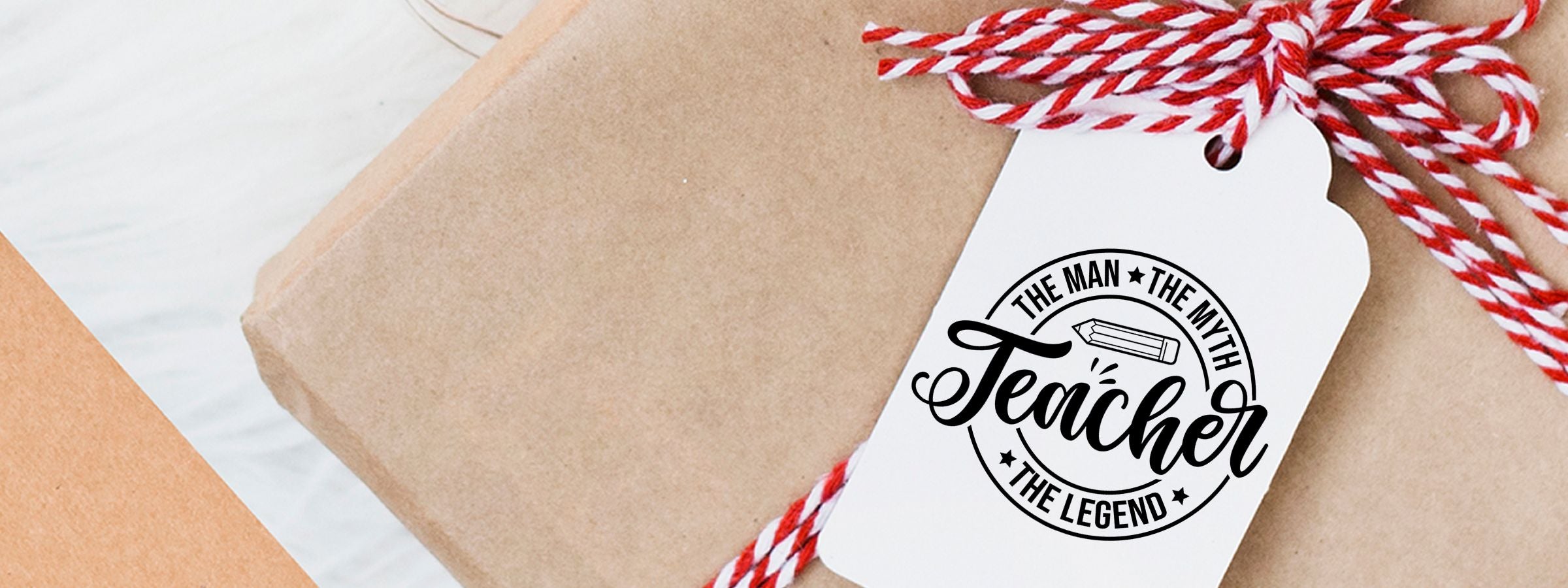 Teacher Craft Stamps white gift tag tied with red-and-white string, reading “The Man, The Myth, Teacher, The Legend” with a pencil icon.