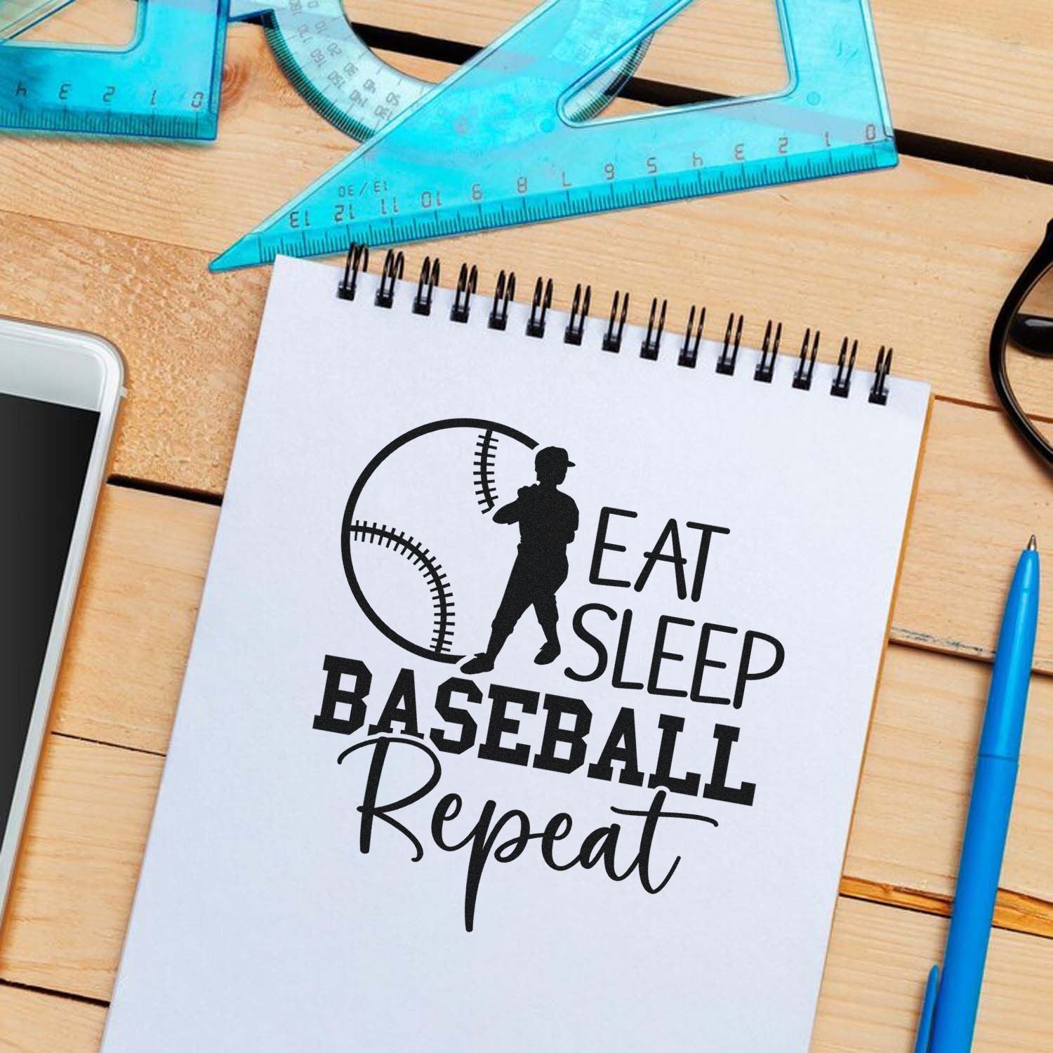 Baseball rubber stamp mockup with Eat Sleep Baseball Repeat slogan on notebook.