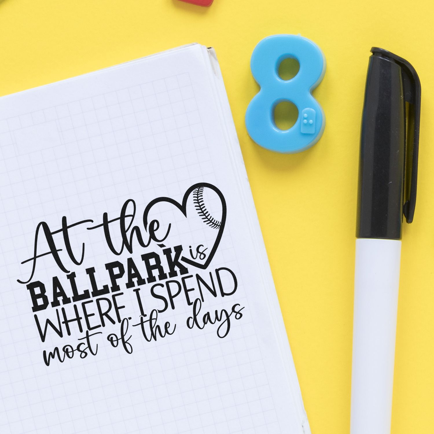 Baseball-themed rubber stamp design on notebook reading At the ballpark is where I spend most of the days beside a pen.