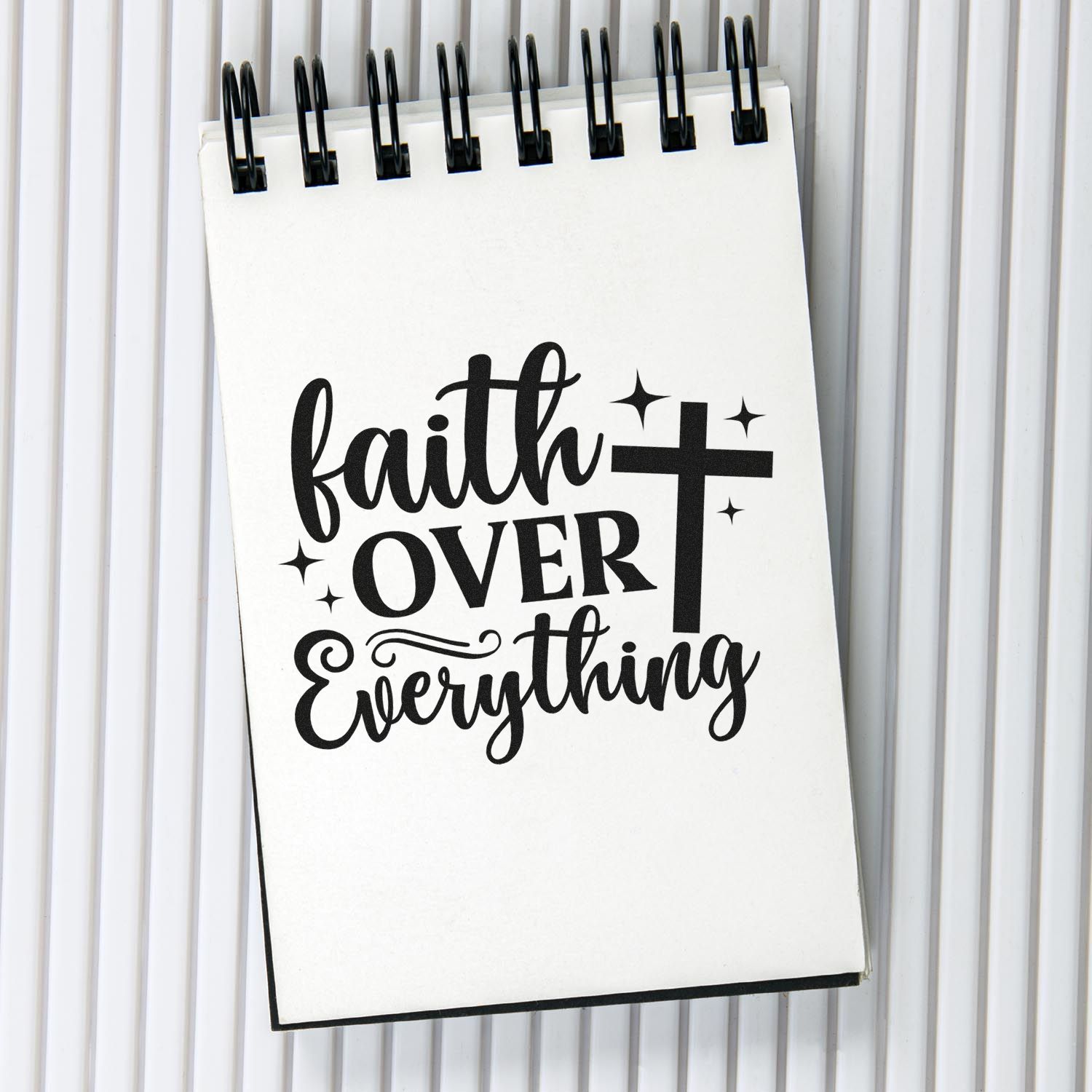 Faith over everything Christian rubber stamp design with cross and stars on a spiral notebook