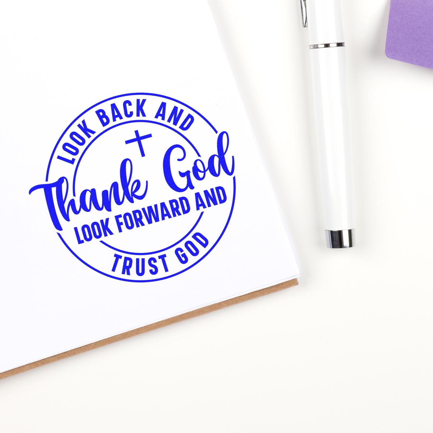Faith-based rubber stamp reading Look back and thank God, look forward and trust God in blue on white paper.