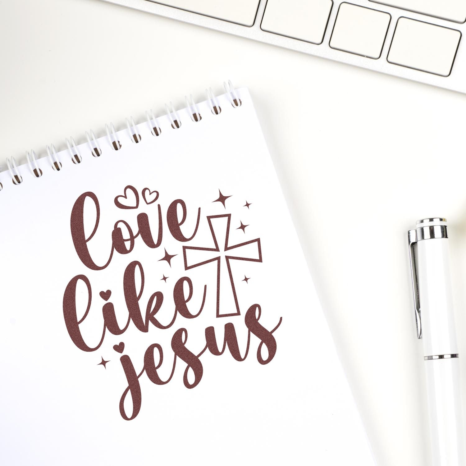 Love Like Jesus rubber stamp design with cross, hearts and sparkles on a notebook, ideal for Christian crafting and journaling.