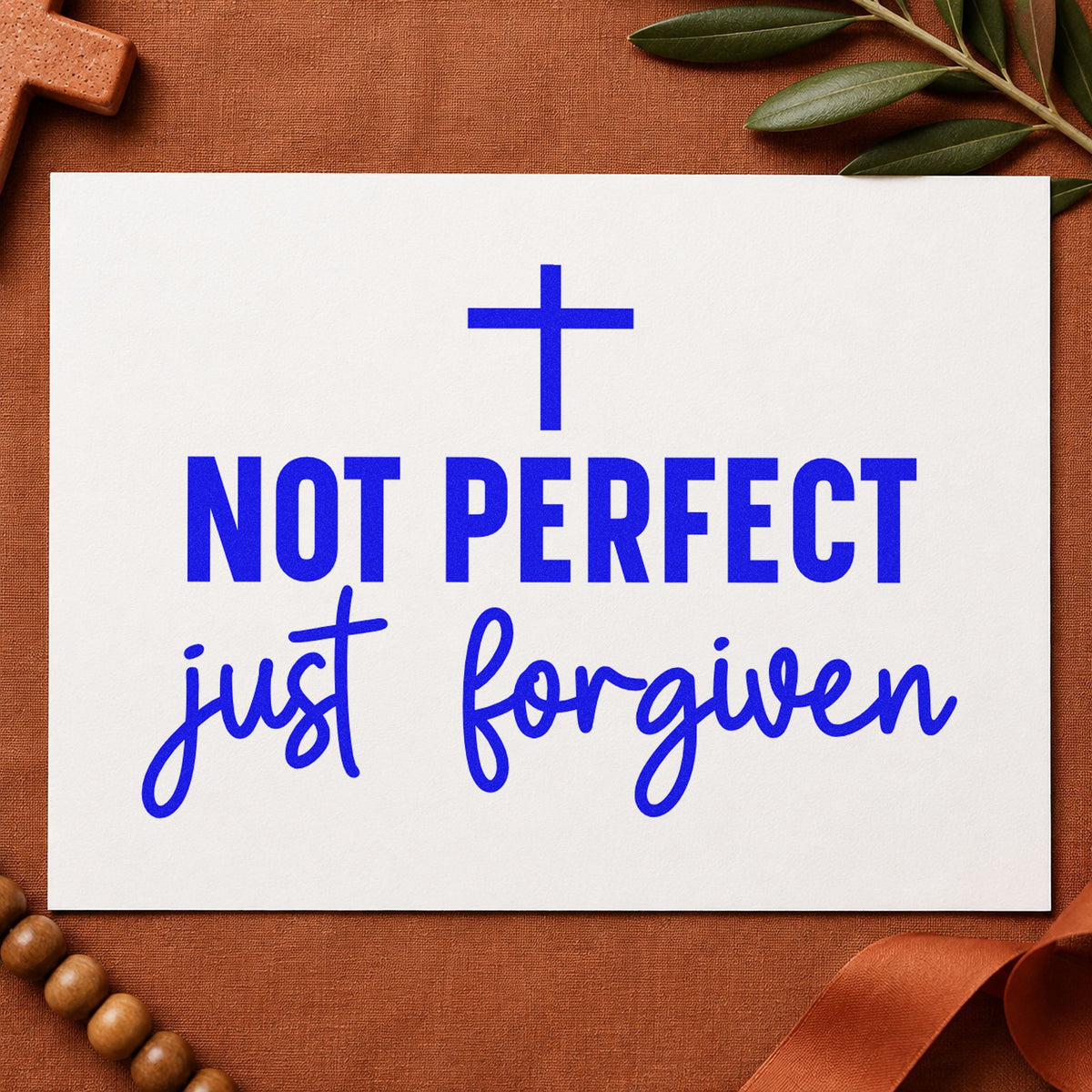 Not Perfect Just Forgiven craft stamp imprinted in blue ink on paper, a design suited to recovery group gifts.
