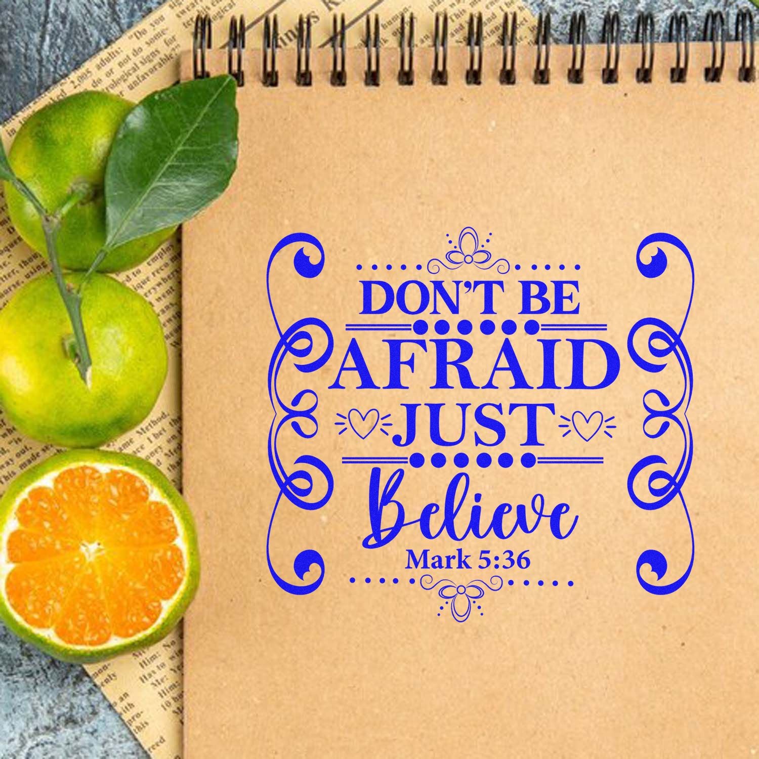 Christian rubber stamp design with blue Dont be afraid, just believe Mark 5:36 quote on kraft notebook page.