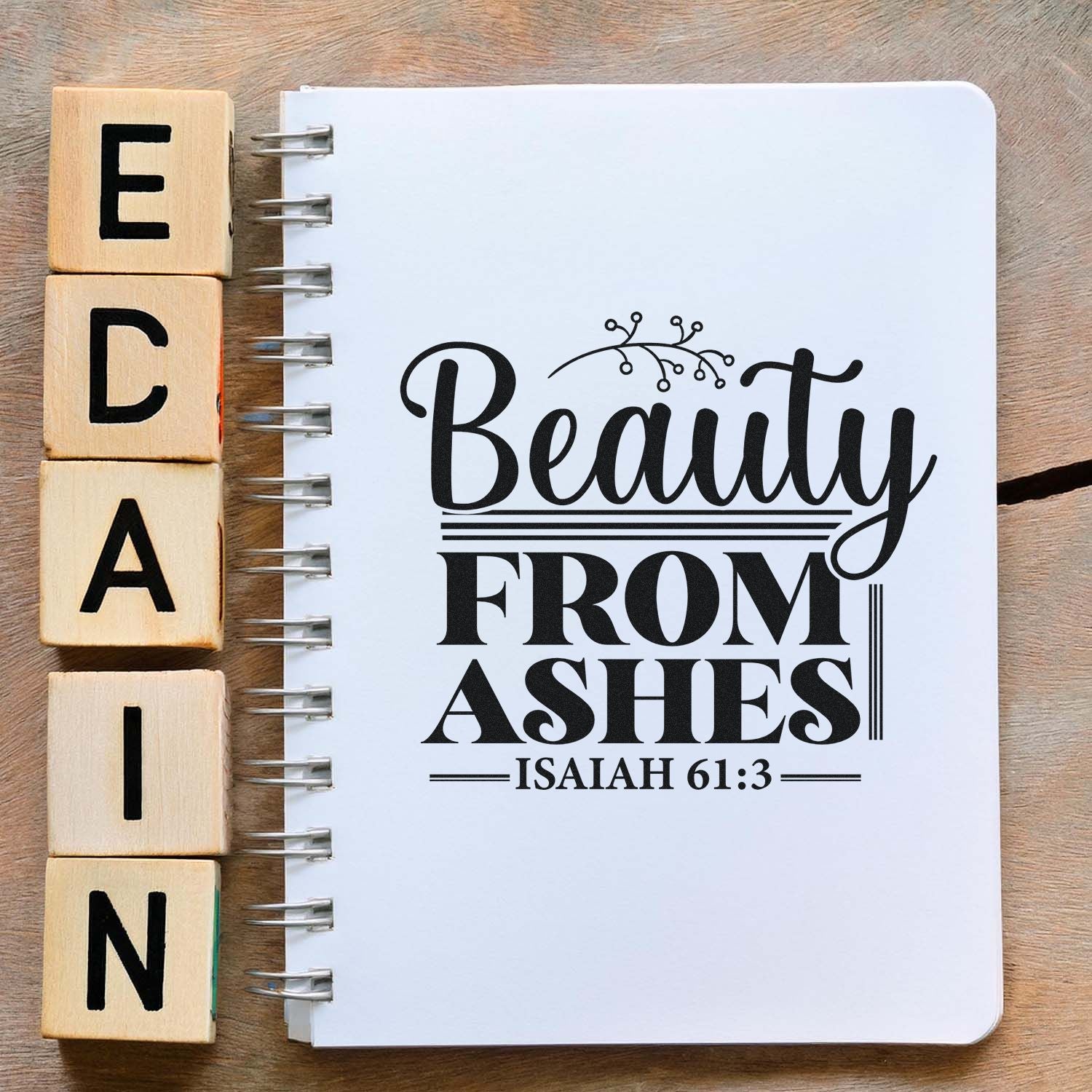 Beauty From Ashes Isaiah 61:3 rubber stamp design on notebook with wooden alphabet blocks, ideal for faith-based crafts and journaling
