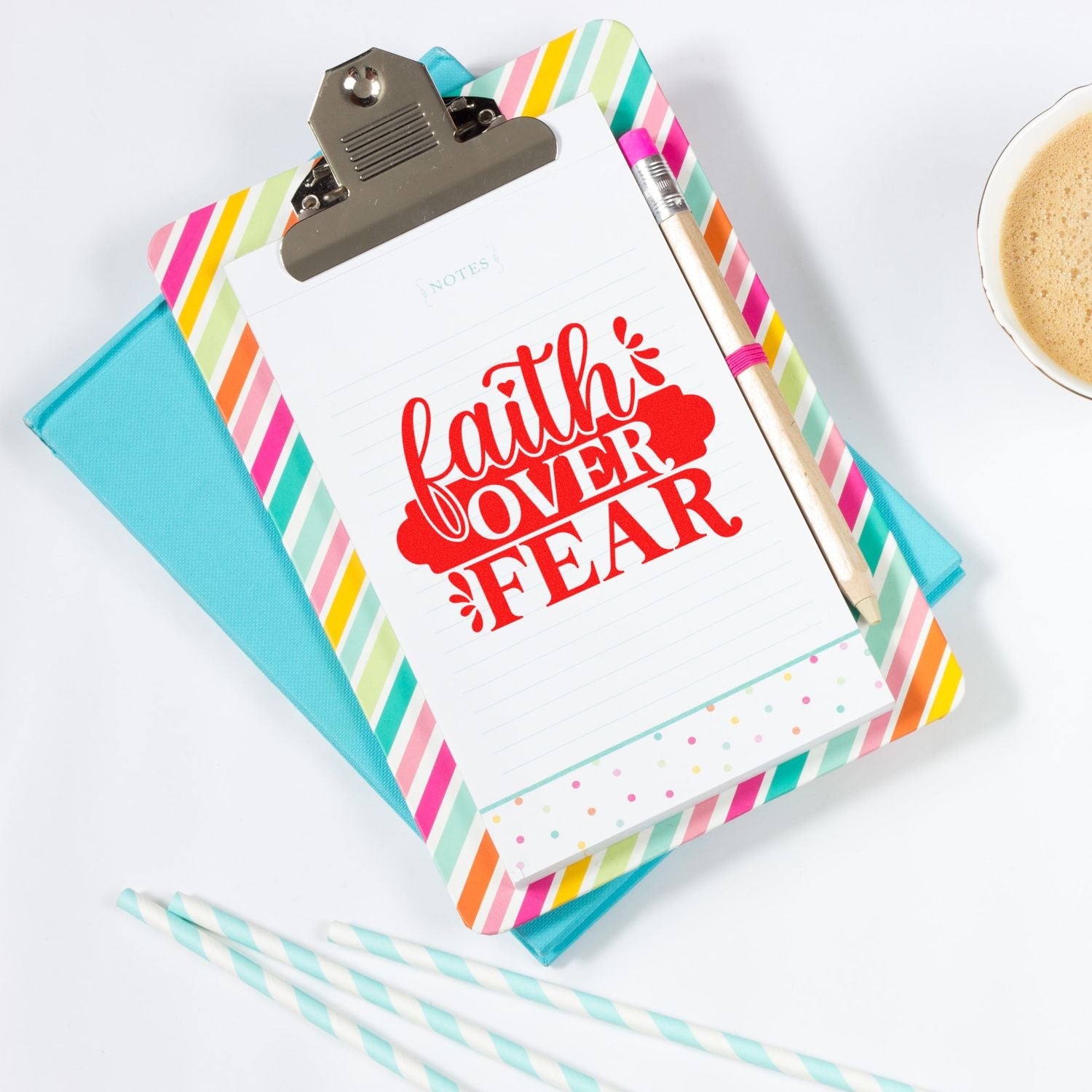 Faith over fear rubber stamp on notepad with colorful clipboard, pencil, and coffee cup for inspirational journaling.