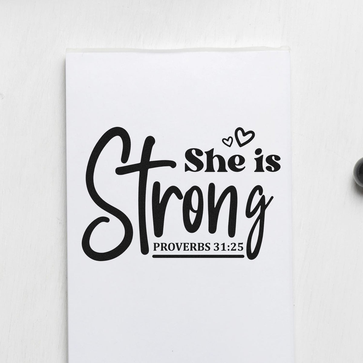 She Is Strong Cross Script Premium Wooden Stamp - Vintage Pro imprint stamped in black ink. A cross forms part of large "Strong" script beside "She is," with hearts and Proverbs 31:25.