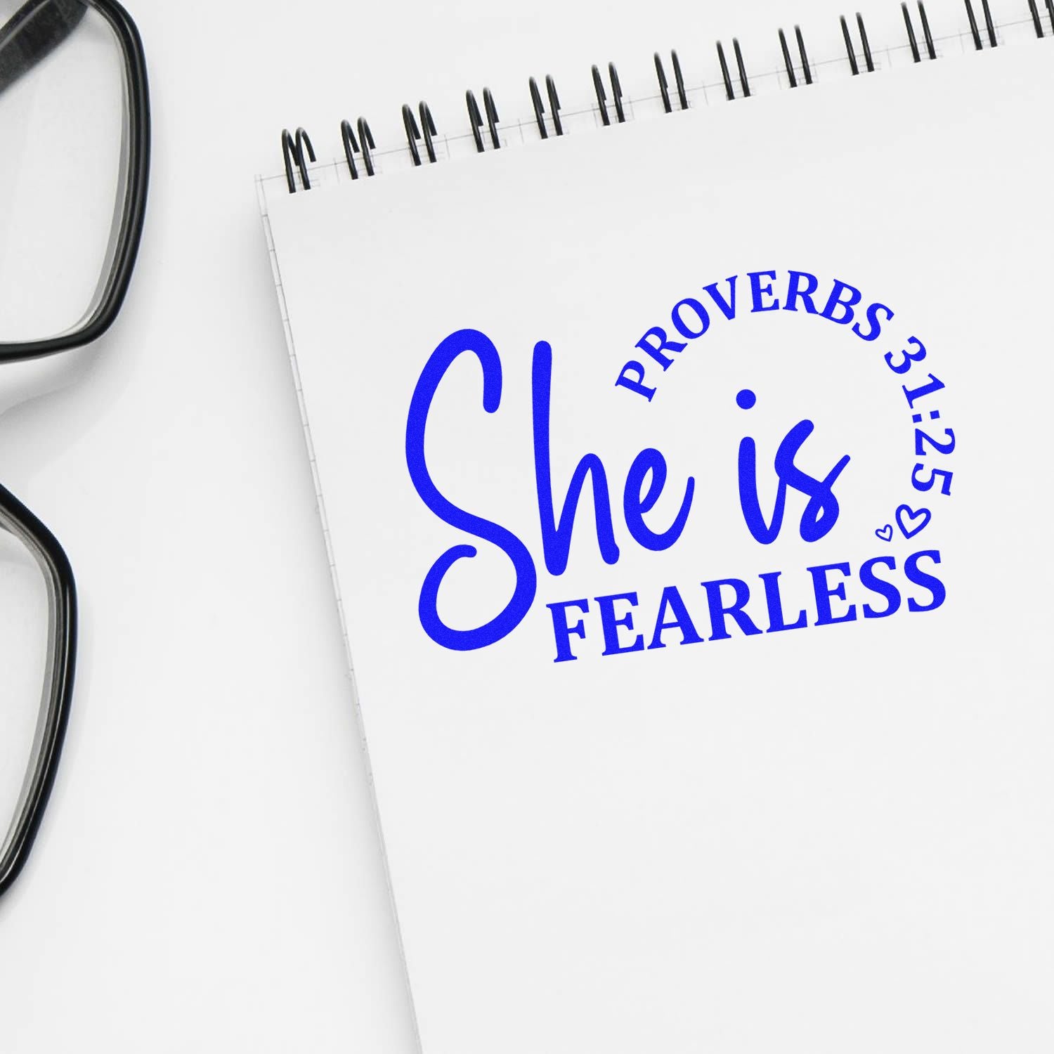 Christian custom rubber stamp with Proverbs 31:25 She is fearless on a notebook.
