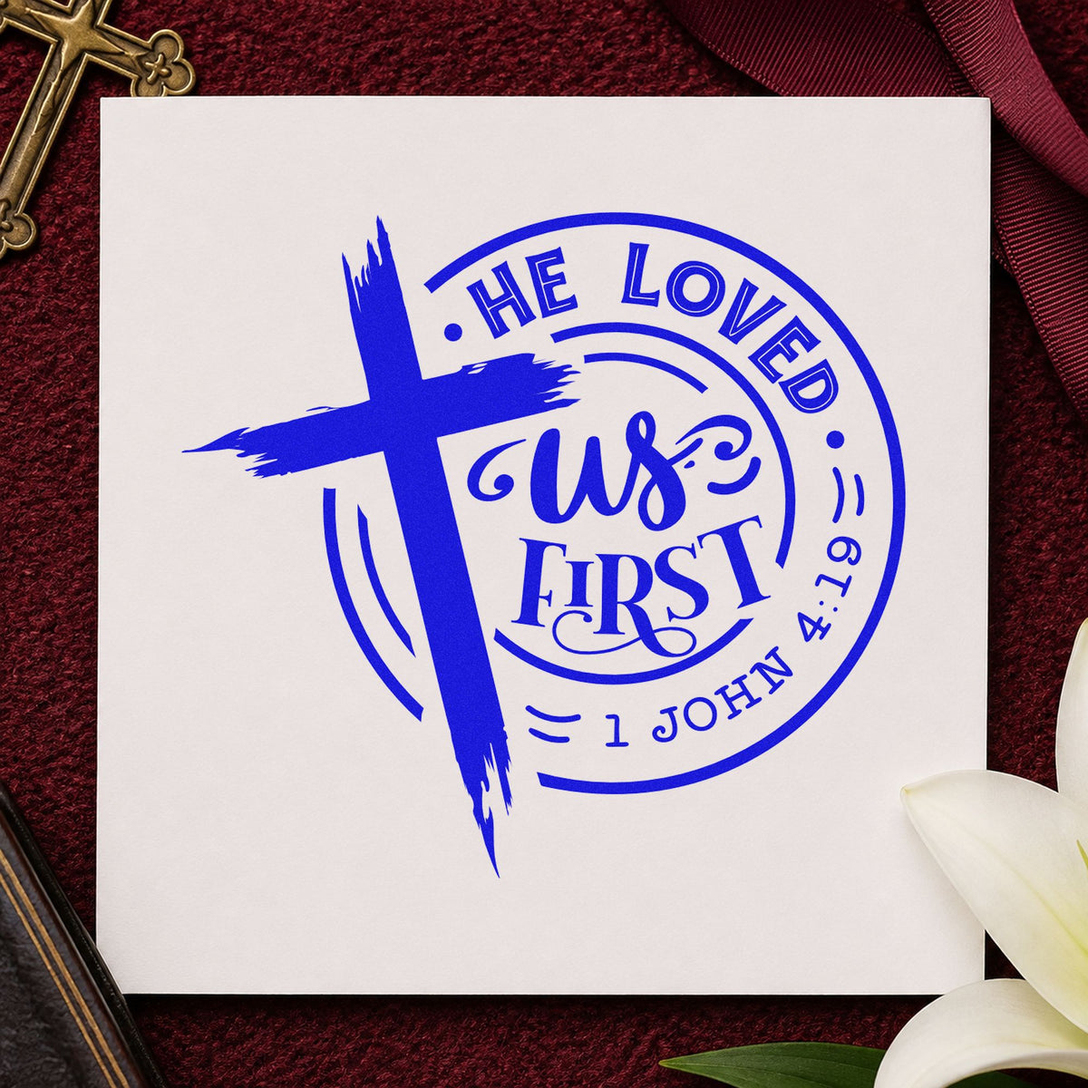 He Loved Us First Badge craft stamp imprinted in blue ink on paper, a design suited to small group handouts.