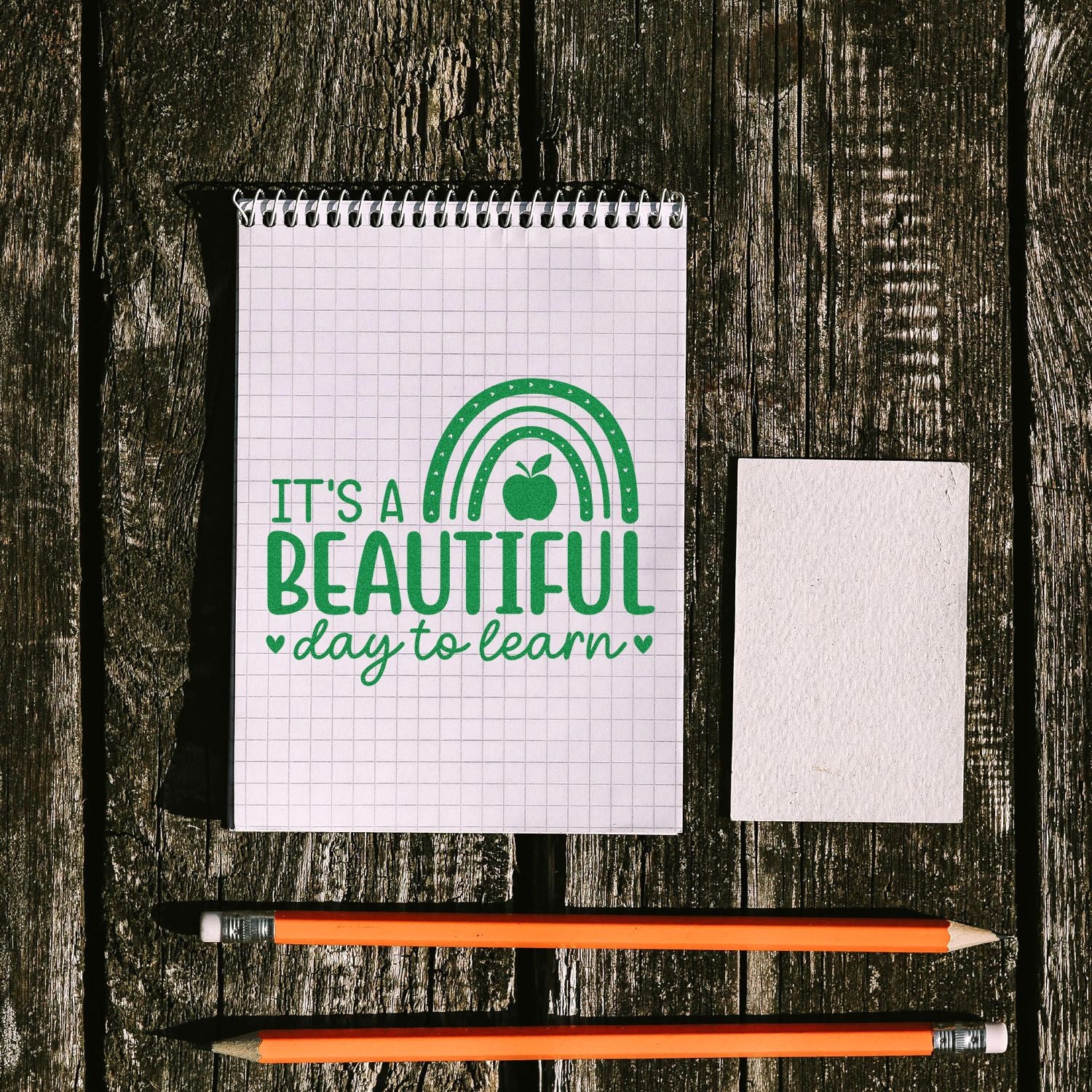 Teacher rubber stamp impression reading Its a Beautiful Day to Learn on notebook with stamp block and pencils.