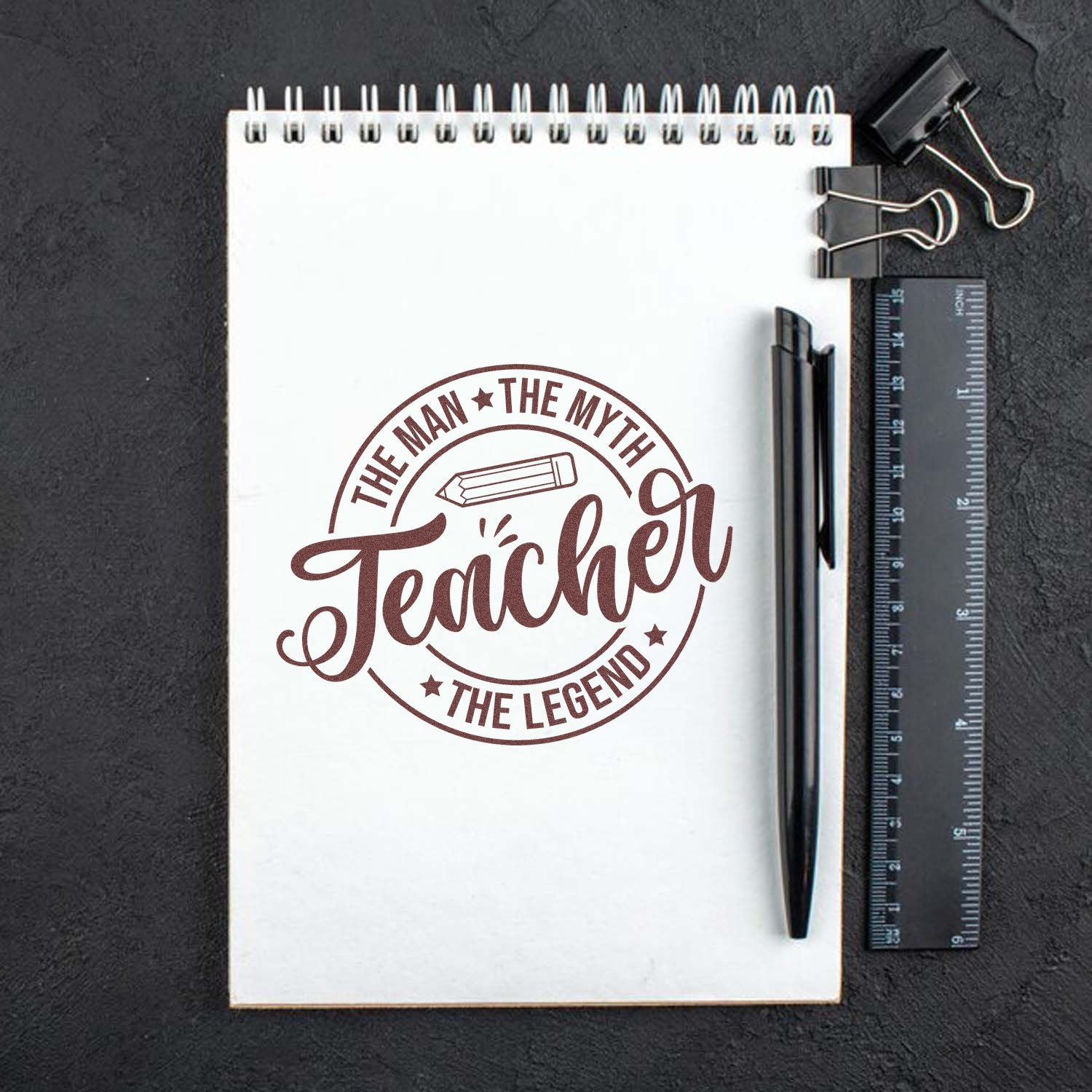 Teacher appreciation rubber stamp design reading The Man, The Myth, Teacher, The Legend on a notebook.