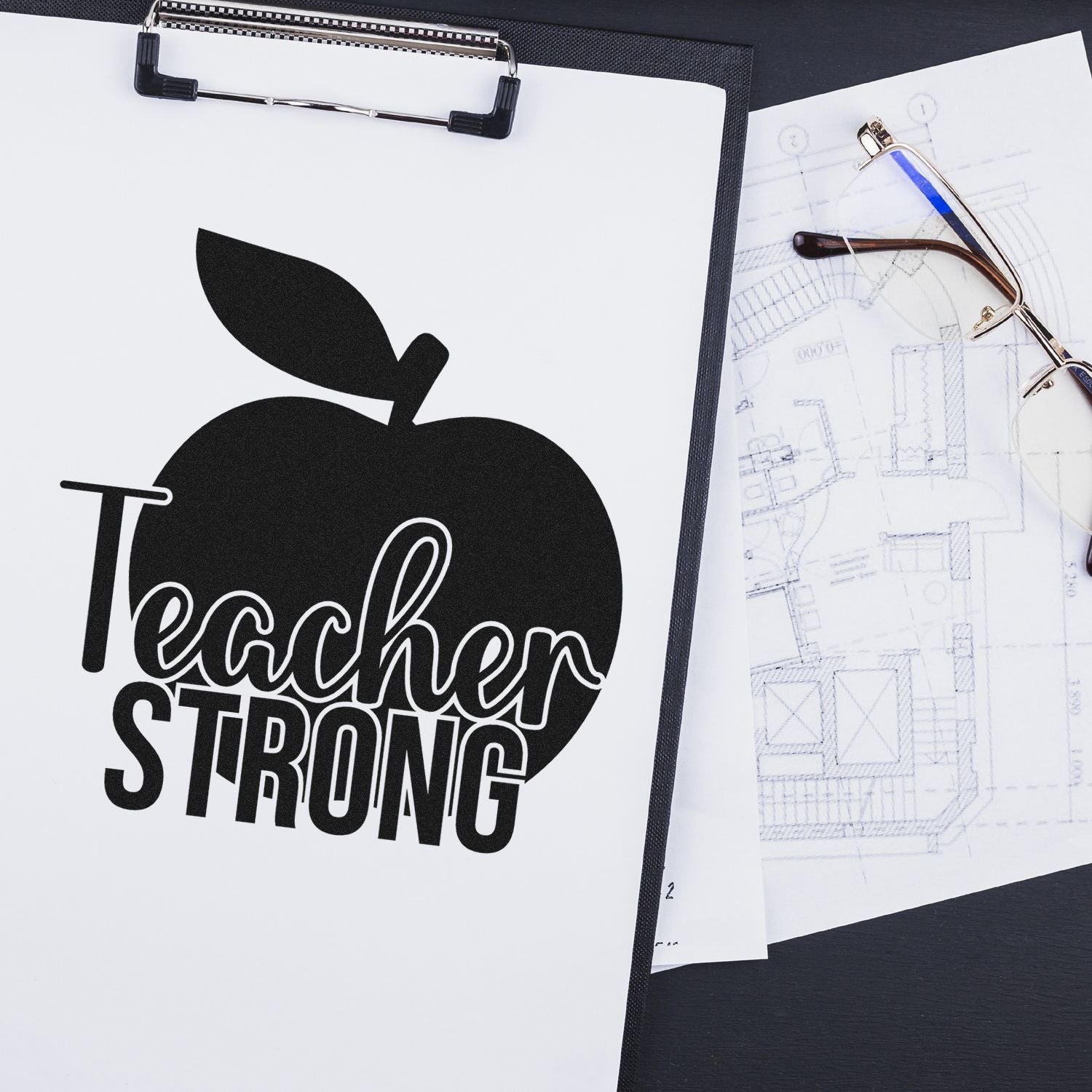 Teacher Strong apple design for custom rubber stamp, shown on a clipboard with eyeglasses and blueprint background.