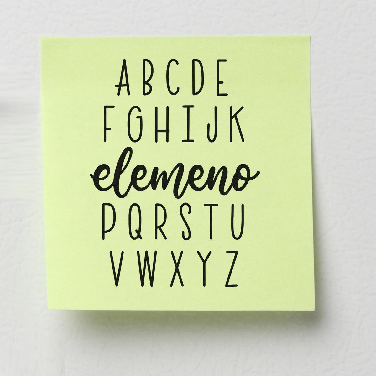 Alphabet Elemeno Premium Wooden Stamp - Vintage Pro imprint stamped in black ink. Rows of alphabet letters surround "Elemeno" in script, replacing the middle alphabet sequence.