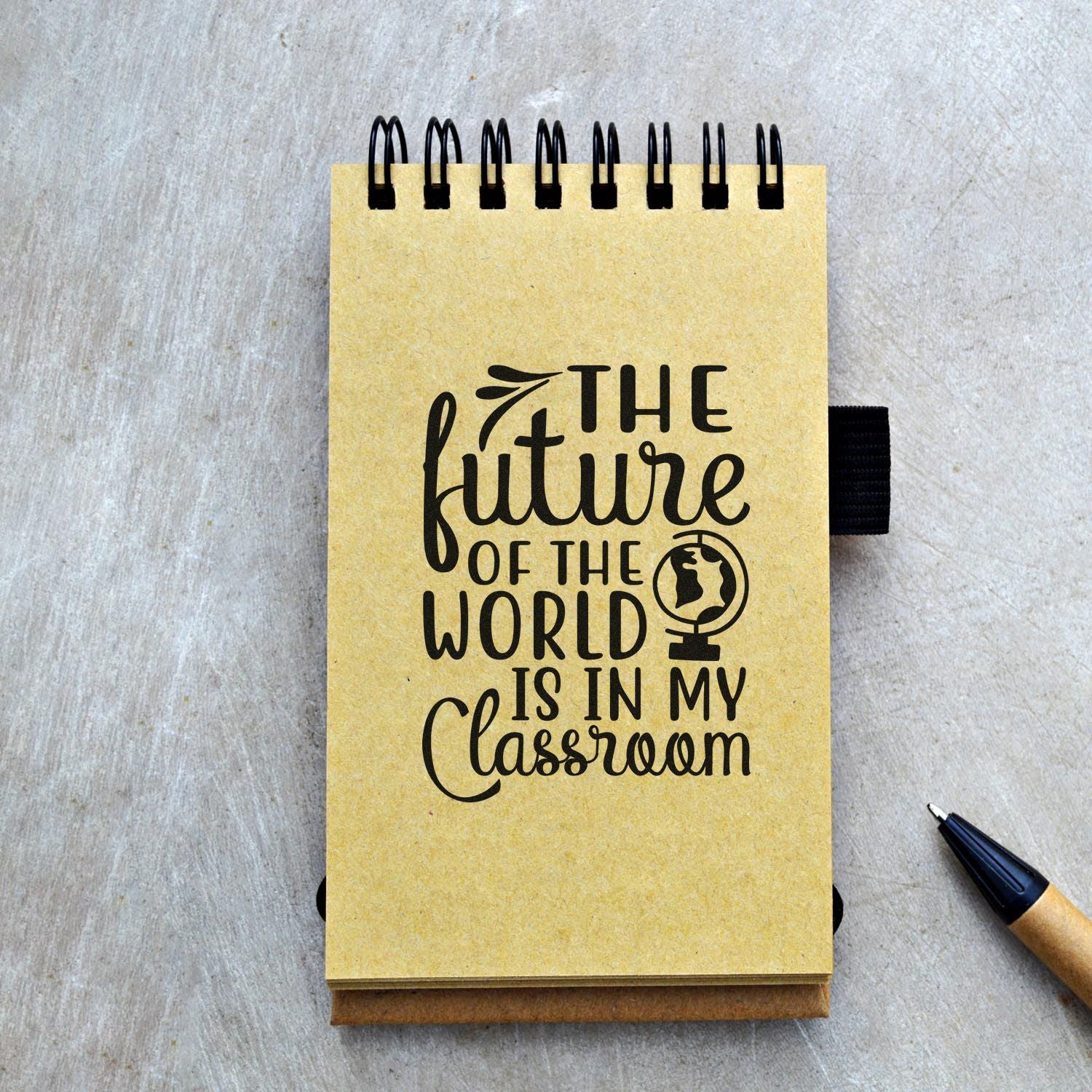 Teacher rubber stamp design with The future of the world is in my classroom on a spiral notebook.