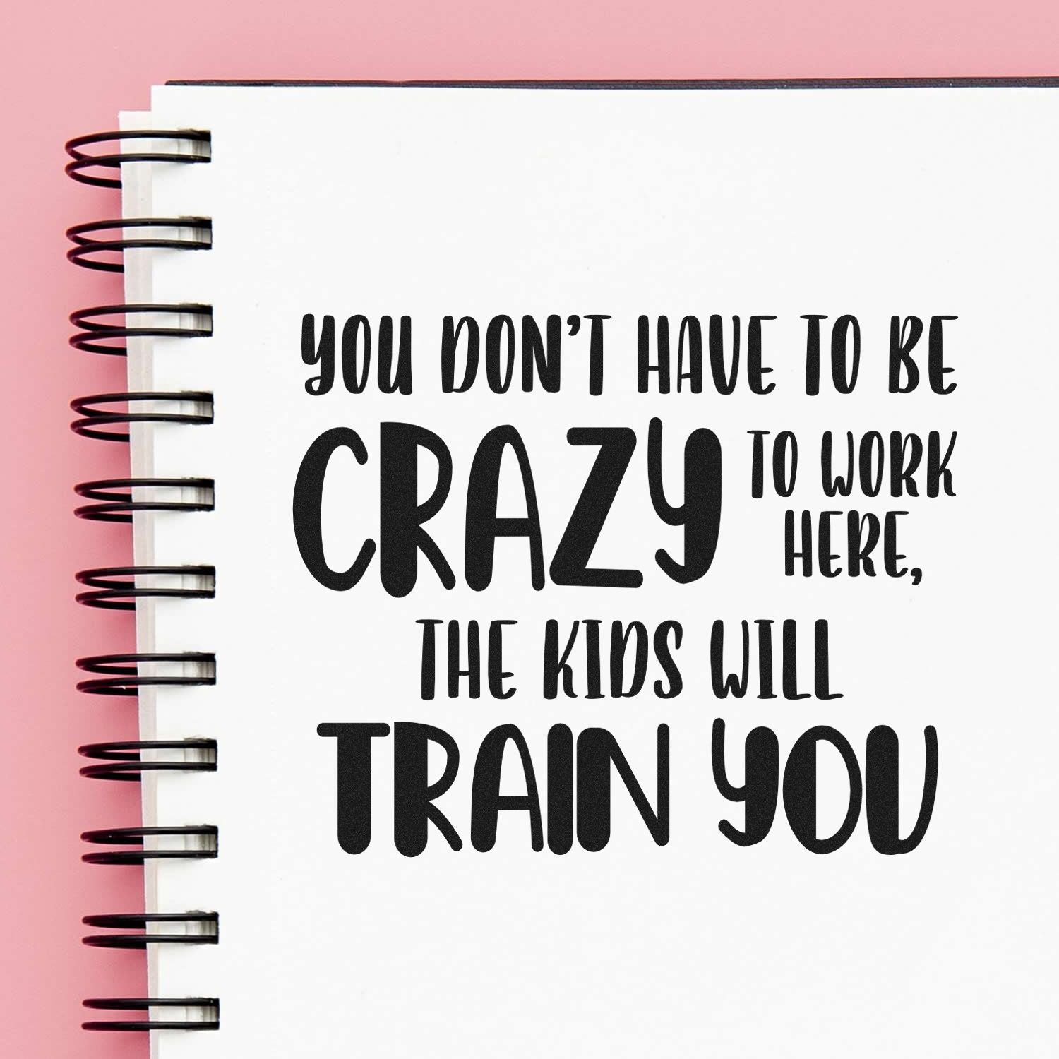 Humorous rubber stamp quote on notebook page: You dont have to be crazy to work here, the kids will train you.