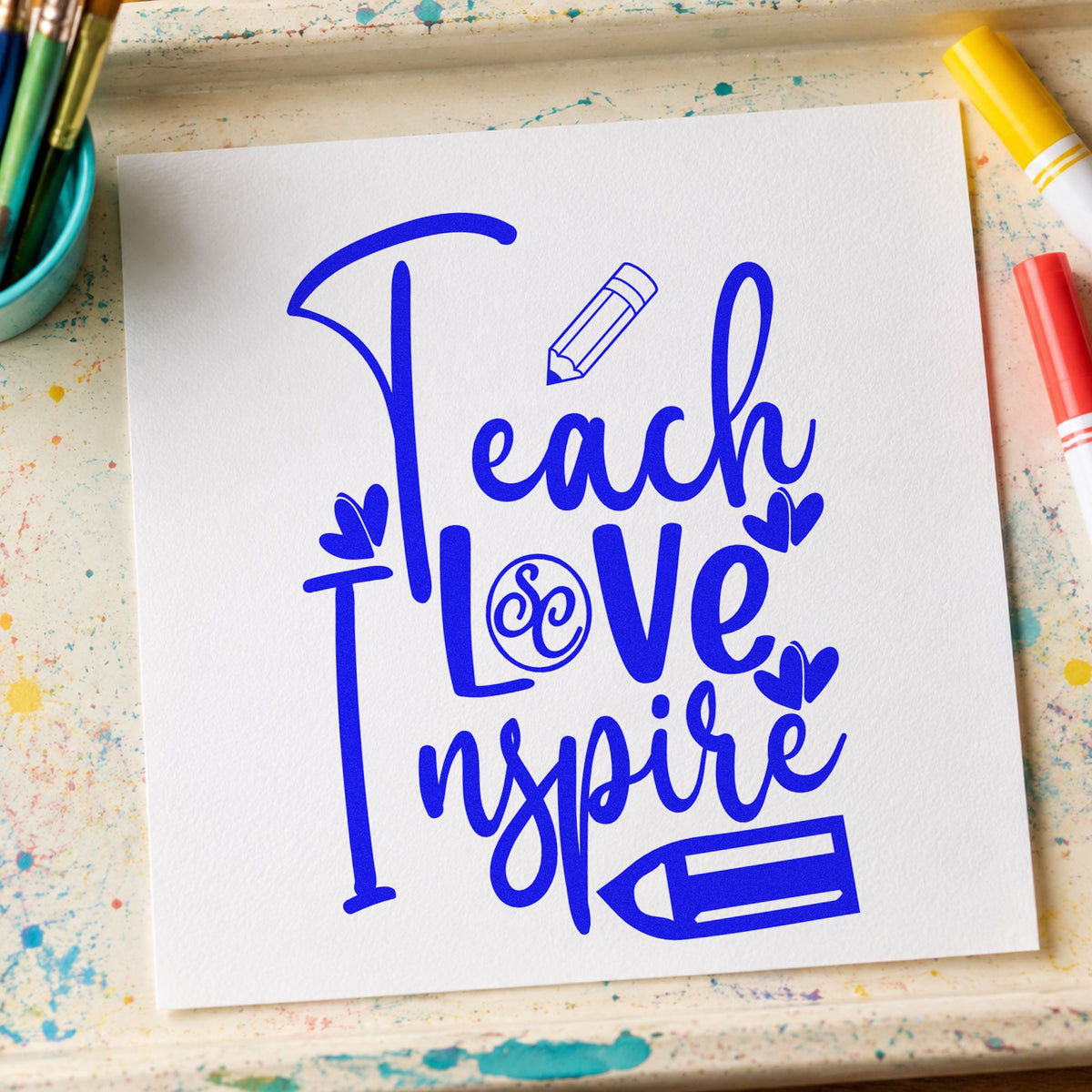Teach Love Inspire Pencil Flourish craft stamp imprinted in blue ink on paper, a design suited to wax letter seals.