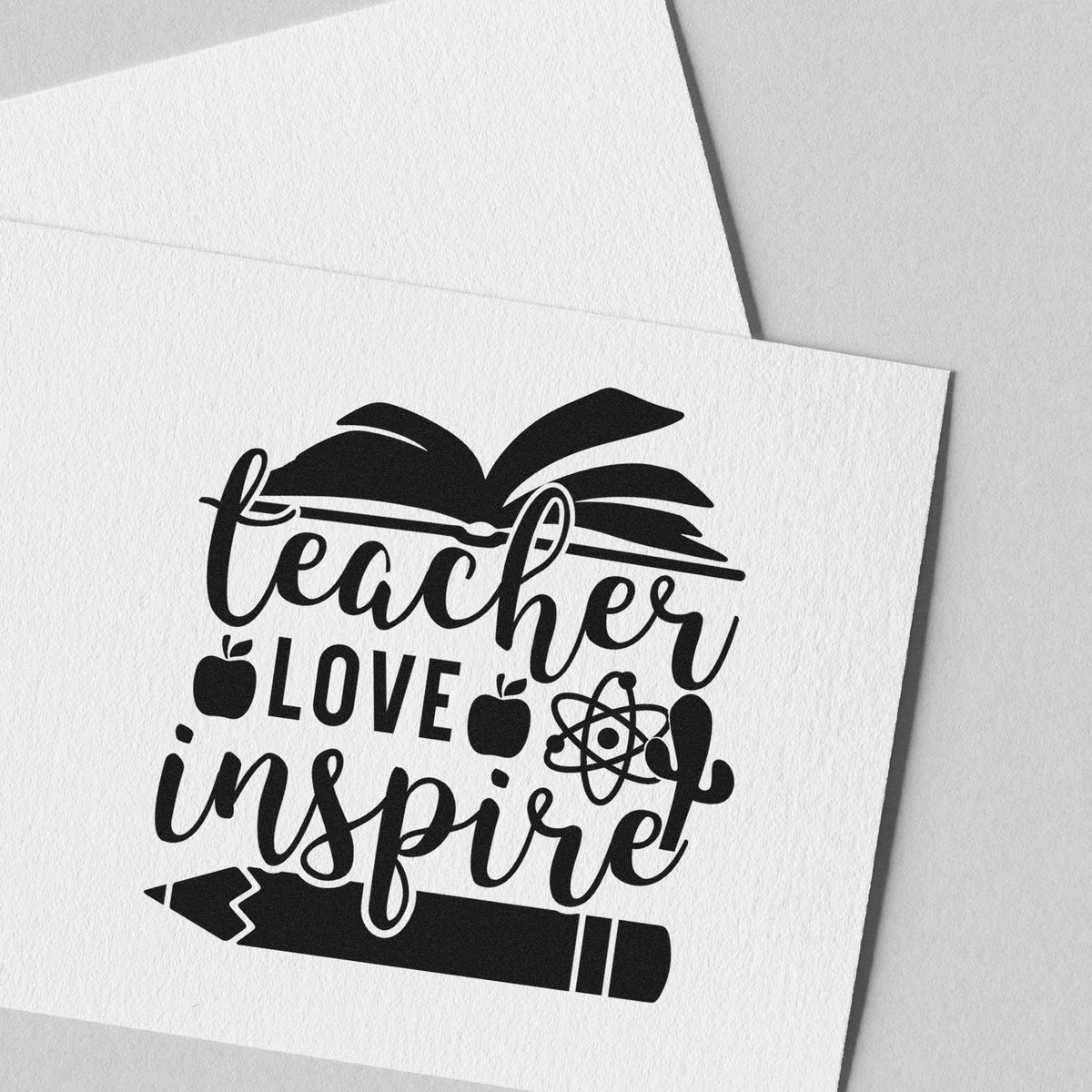 Teacher Love Inspire Learning Icons Premium Wooden Stamp - Vintage Pro imprint stamped in black ink. "Teacher Love Inspire" features an open book, apples, atom symbol, and large pencil.