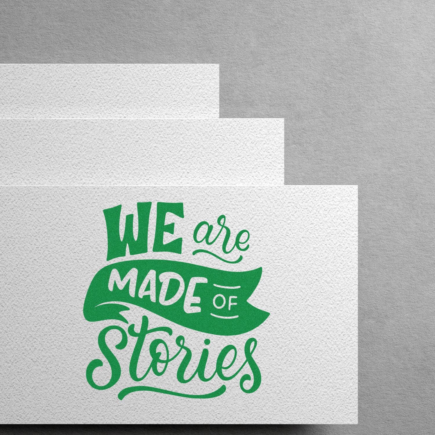 Custom rubber stamp design with green We are made of stories lettering on textured paper mockup.