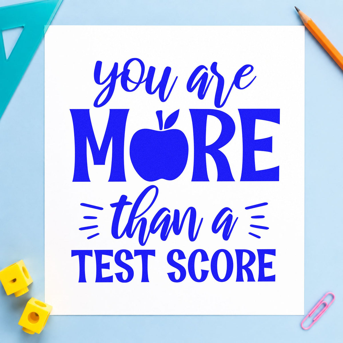 More Than A Test Score craft stamp imprinted in blue ink on paper, a design suited to envelope slip seals.