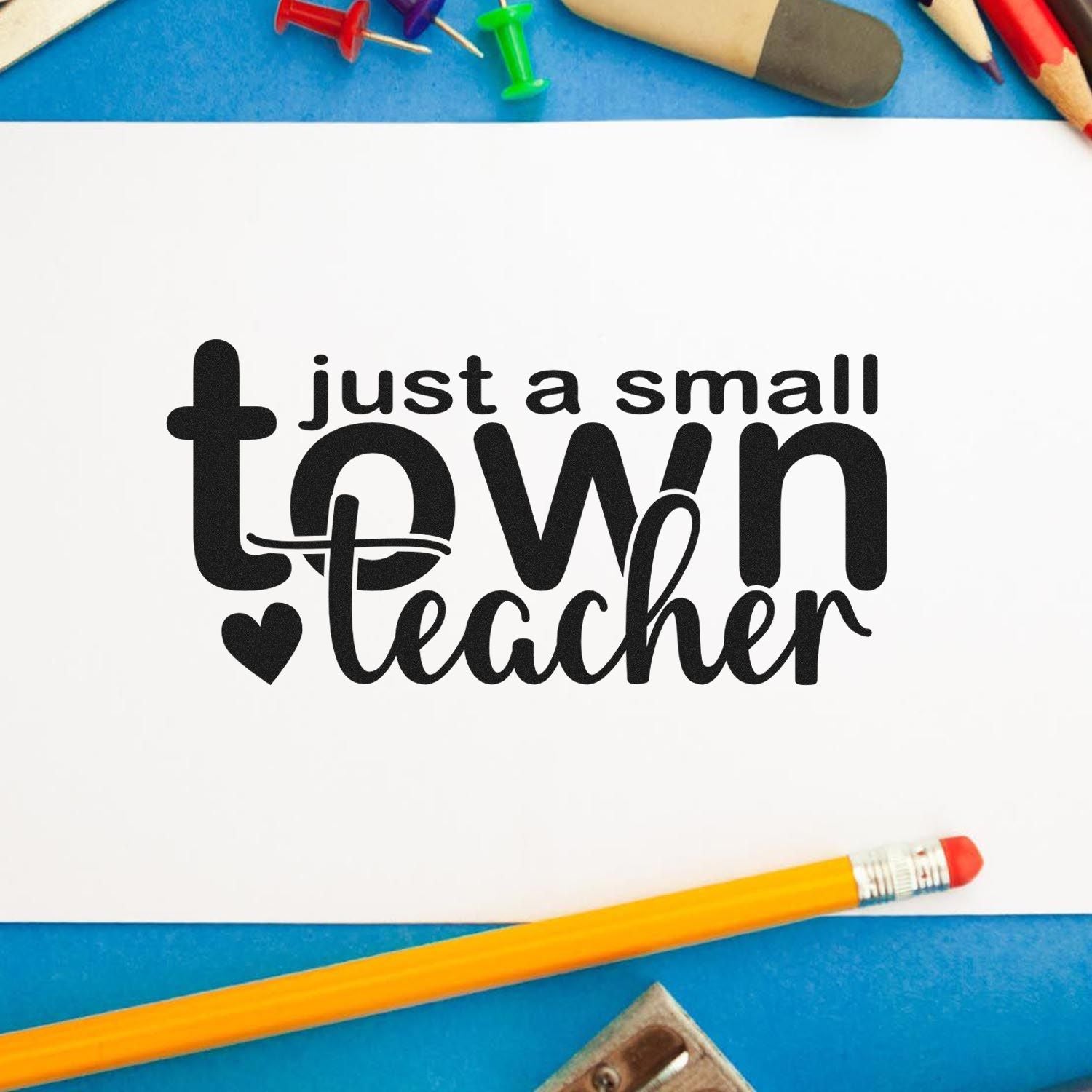 Small town teacher rubber stamp design with black text on white paper, surrounded by school supplies for classroom crafts and teacher gifts.